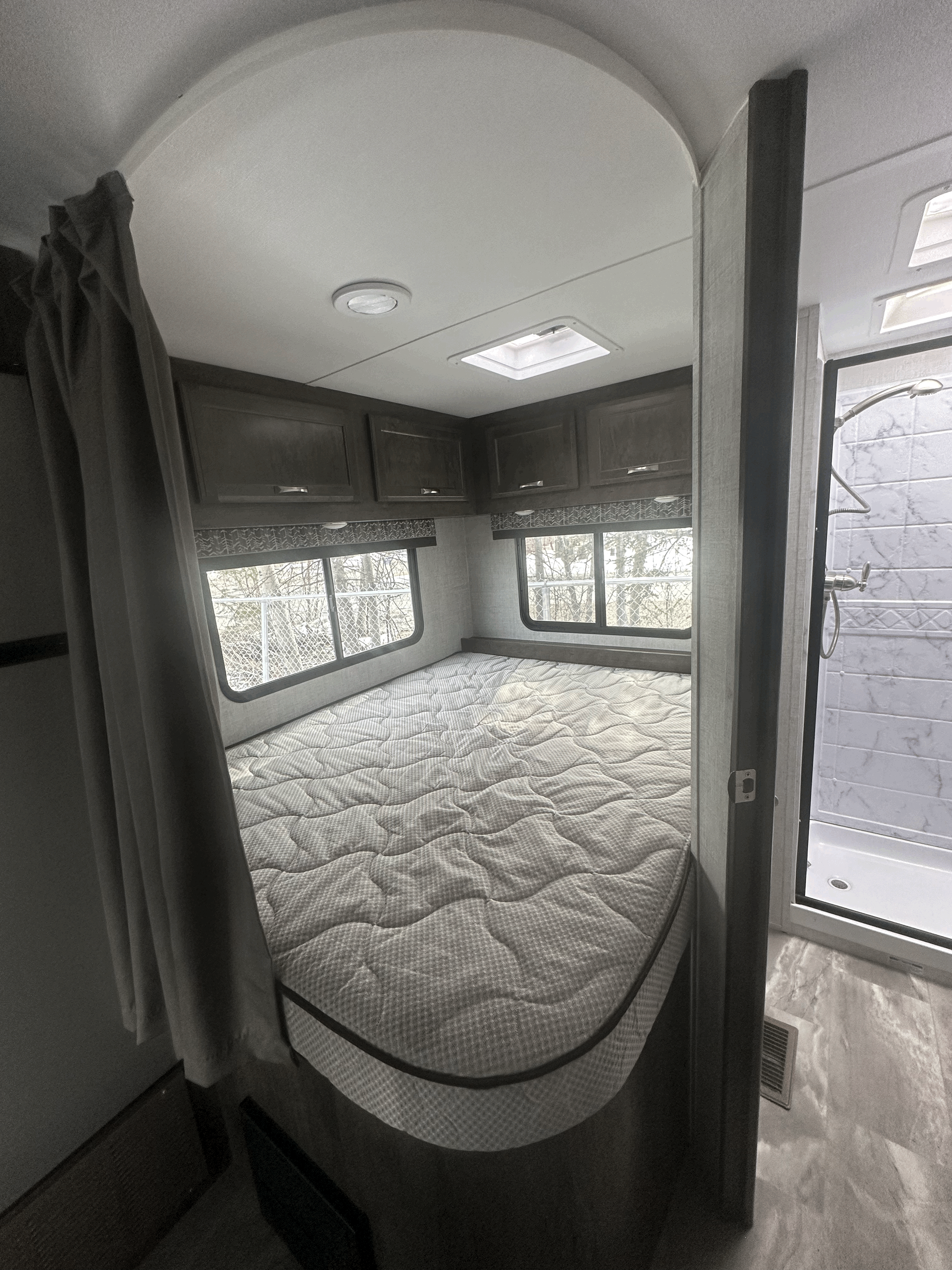 Experience comfort in this RV rental! Cozy bedroom with windows & overhead storage, plus an adjacent modern shower.. Gulf Stream Conquest 2022