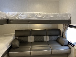 This RV rental interior features comfortable bunk beds over a versatile sofa, ready for your next adventure.. Forest River Wildwood X-lite 273QBXL 2023