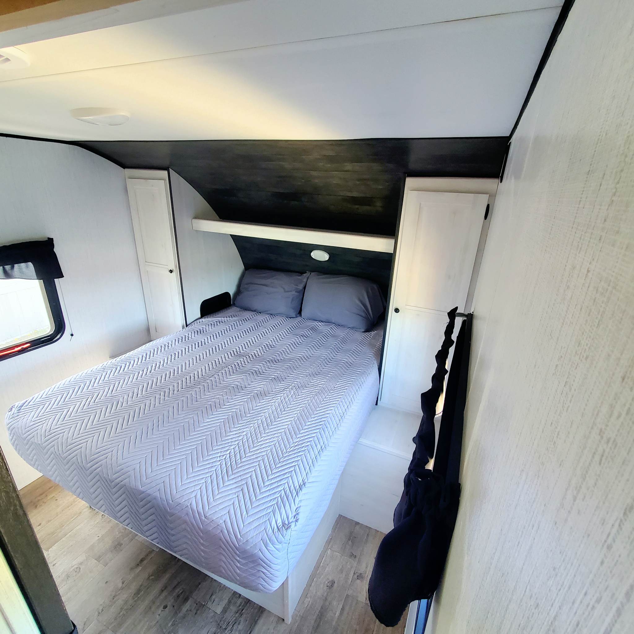 Cozy RV rental bedroom with a comfy bed, storage, and window, perfect for your next adventure.. Heartland 261 JM 2023