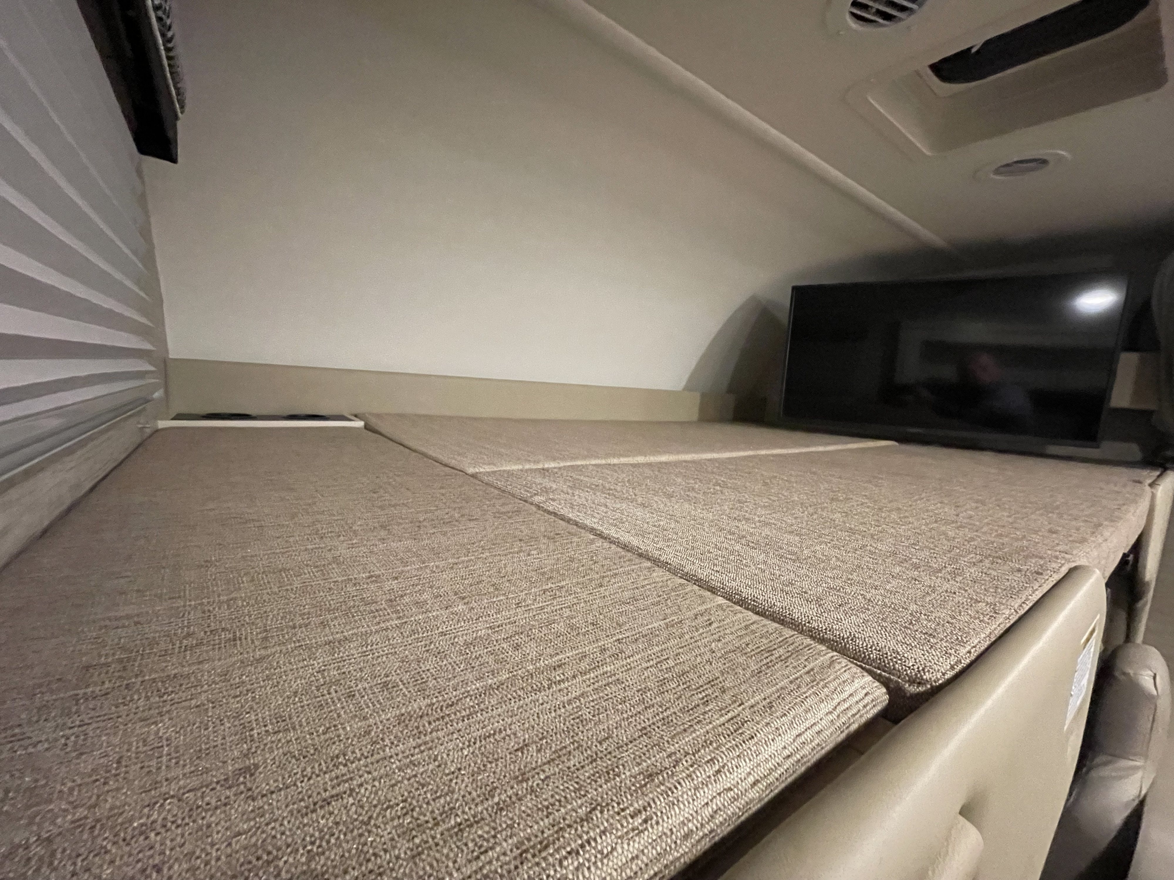 Cozy RV rental cab-over bunk bed with TV and window blinds, perfect for a good night's sleep.. Thor Chateau 2022