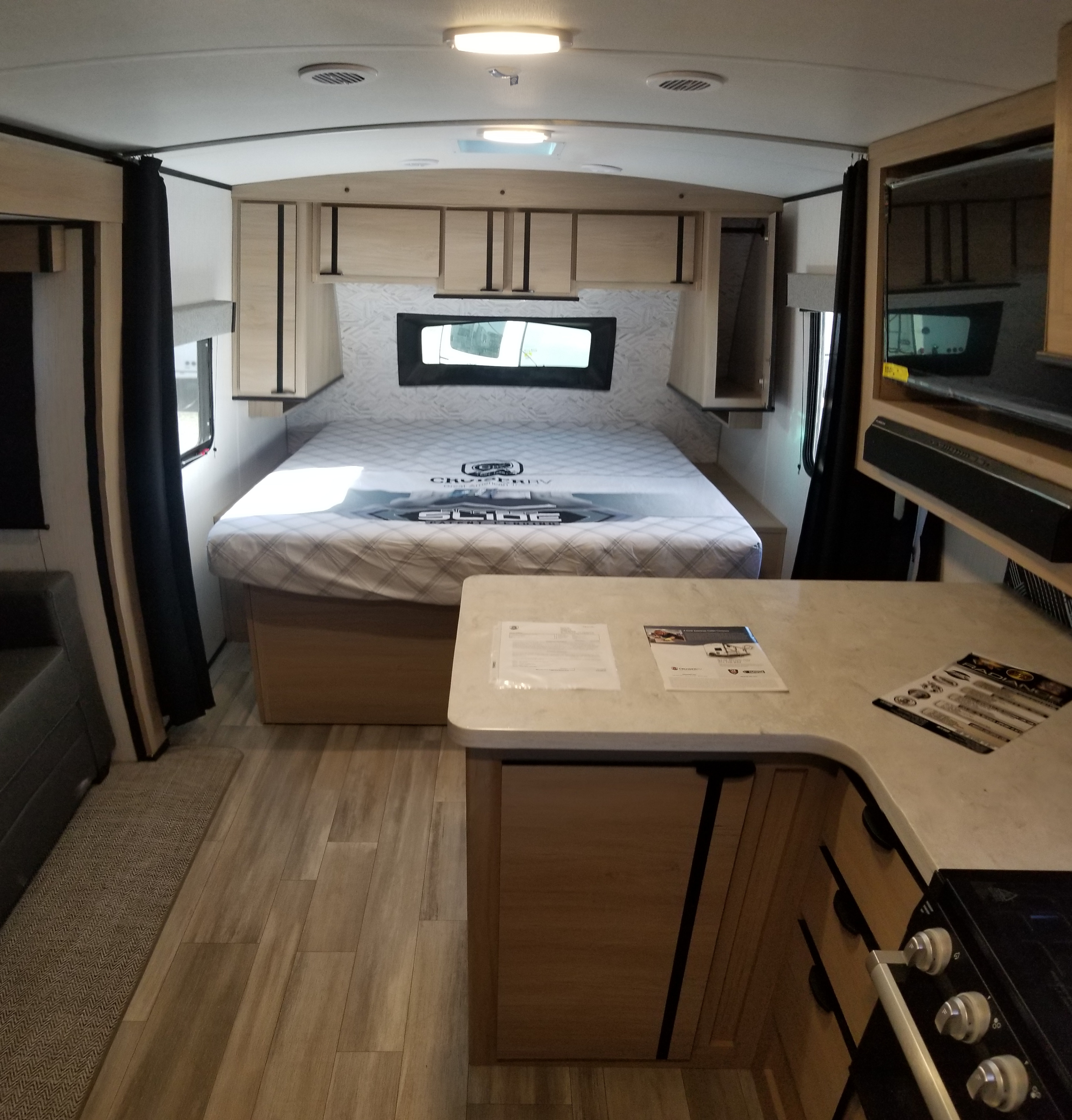 Inside a modern RV rental: view of a comfortable bedroom with bed & storage, alongside a well-equipped kitchen area.. Cruiser Rv Corp Radiance 2022