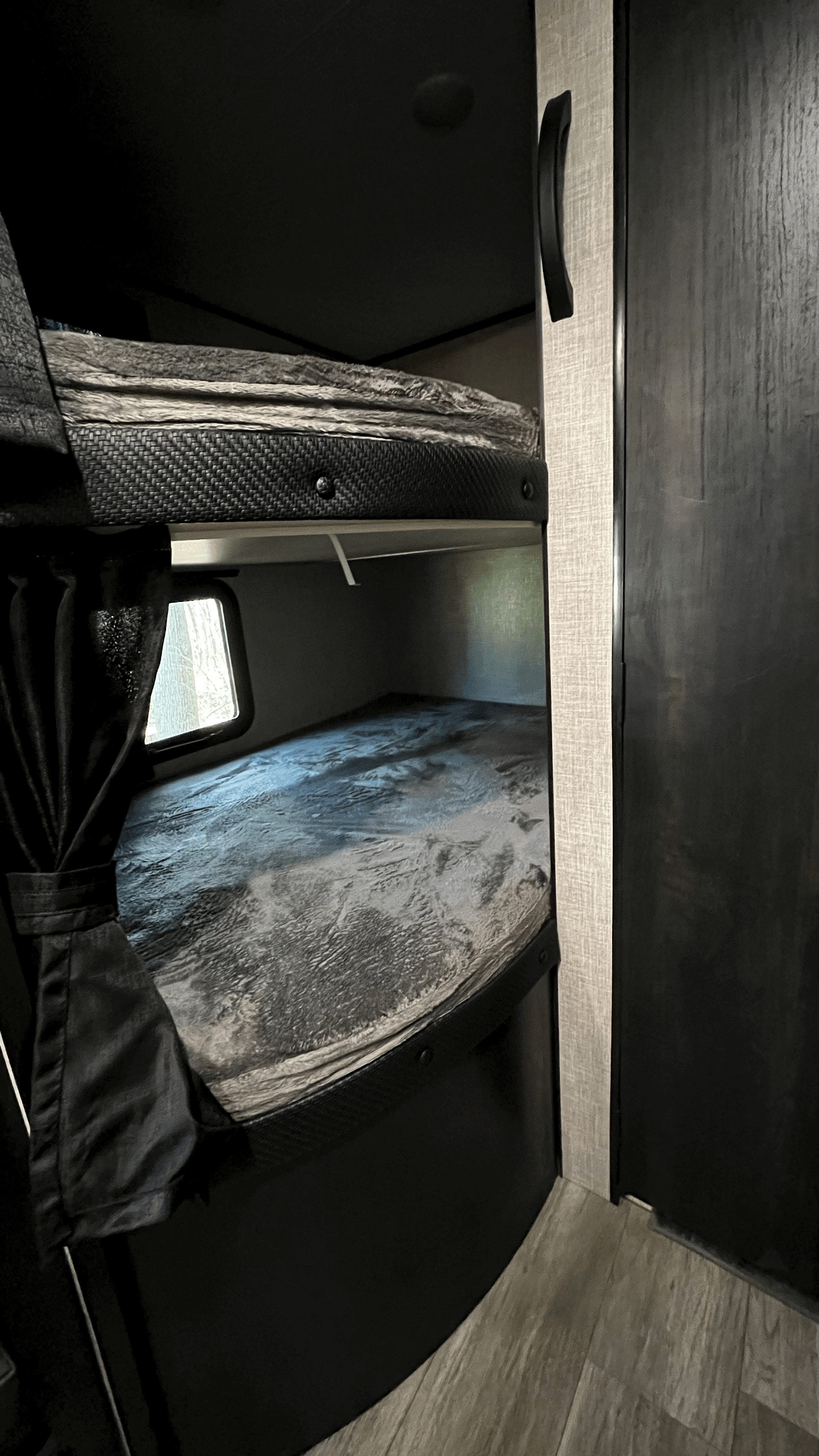 Inside an RV rental: two bunk beds with stylish grey bedding, a window with curtains, and modern cabinetry.. Jayco Jay Flight SLX 2022