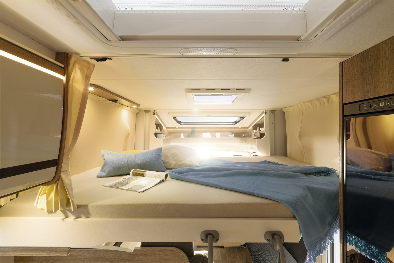 Spacious RV sleeping area with cozy bed, blue blanket, and skylights; ideal for your next rv rental trip.. Dethleffs Trend T7057EB 2023