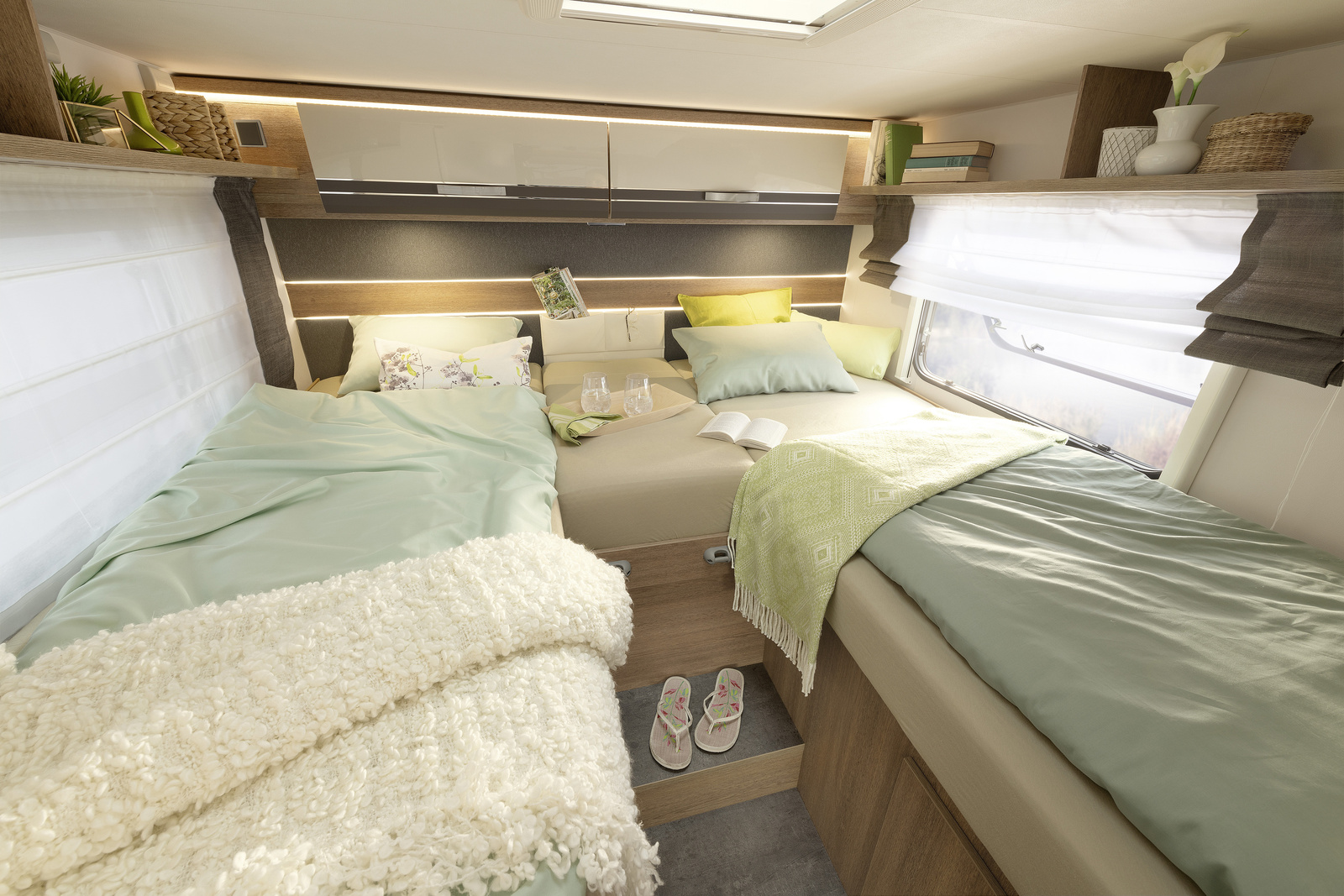 Spacious RV rental bedroom featuring two comfortable single beds with mint green bedding and ample overhead storage.. Dethleffs Trend 7057eb 2023