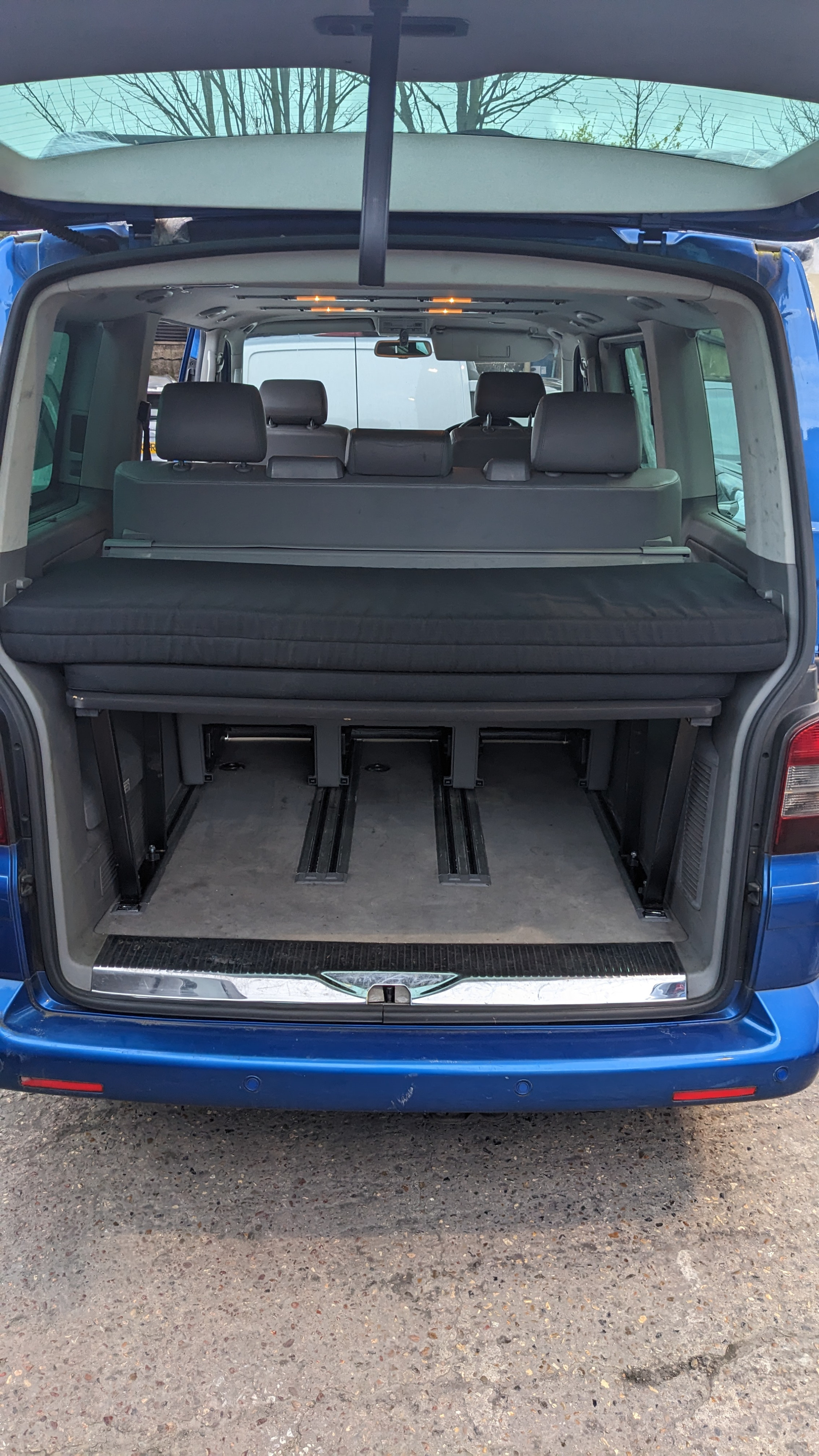 View into a blue van's open tailgate showing a folded bed/mattress above a cargo area with tracks. Great for an rv rental.. Volkswagen Other 2006