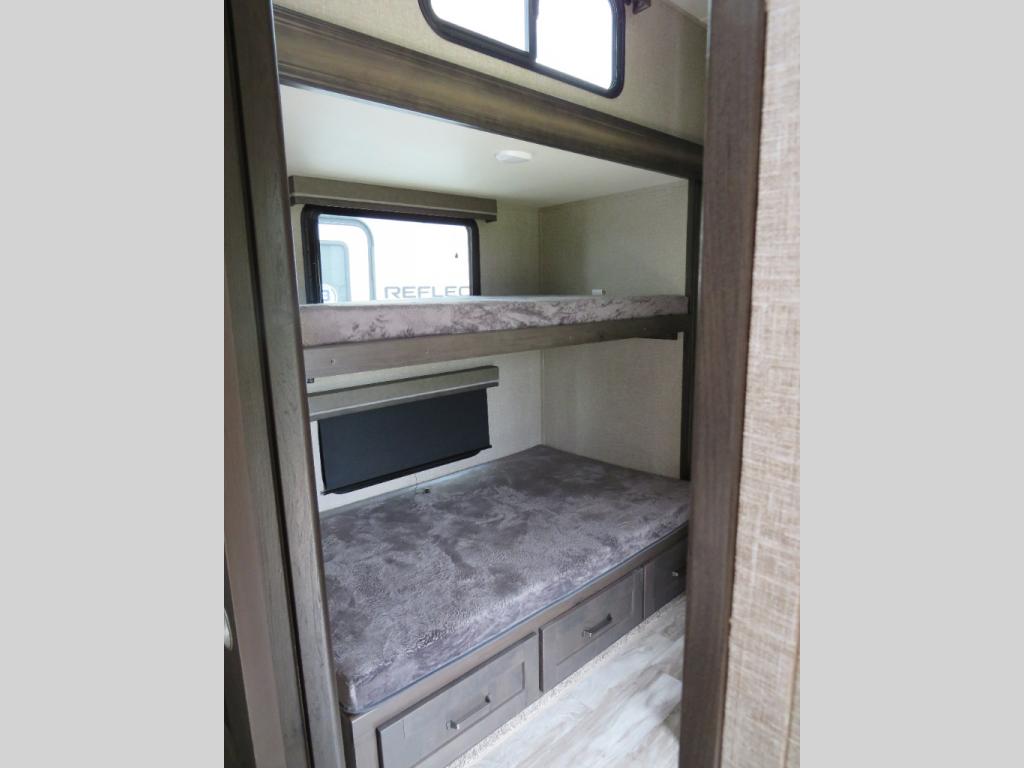 RV rental interior: A compact bunk bed area with two bunks, window, and lower bed storage drawers, ideal for a camper.. Grand Design Reflection 2022