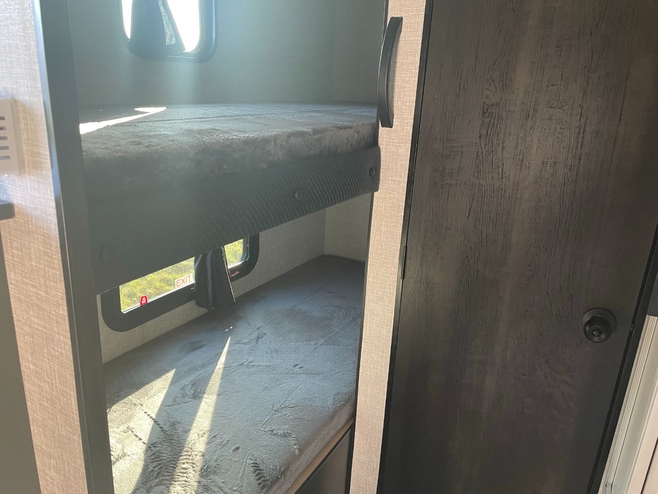Inside an RV rental: two sunlit bunk beds. The lower bunk features an emergency exit window, ideal for family adventures.. Jayco Jay Flight SLX 2022