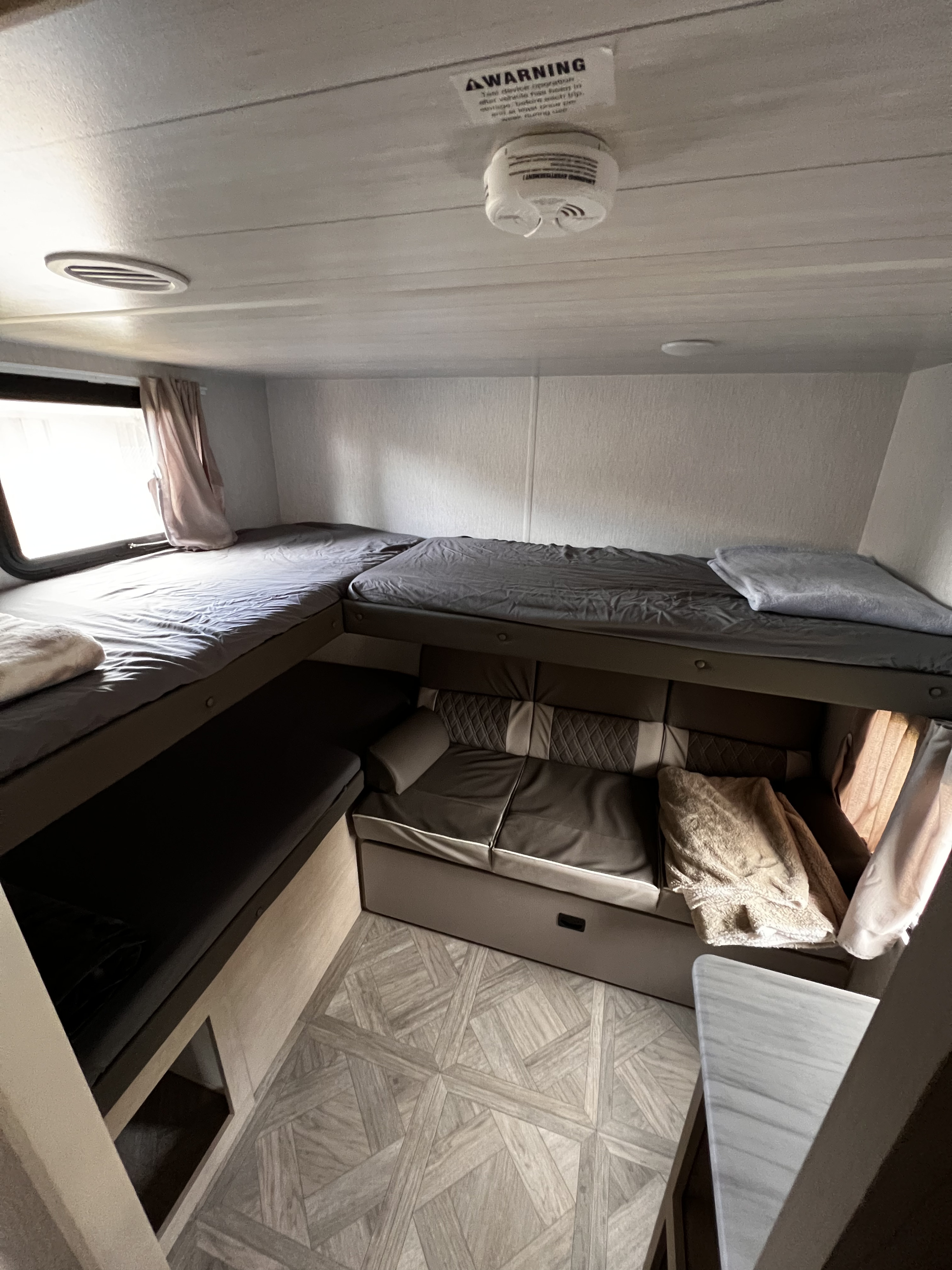 Cozy RV rental interior featuring multiple bunk beds, a sofa, and a patterned floor, creating a versatile sleeping and living space.. Forest River Salem Cruise Lite 2023