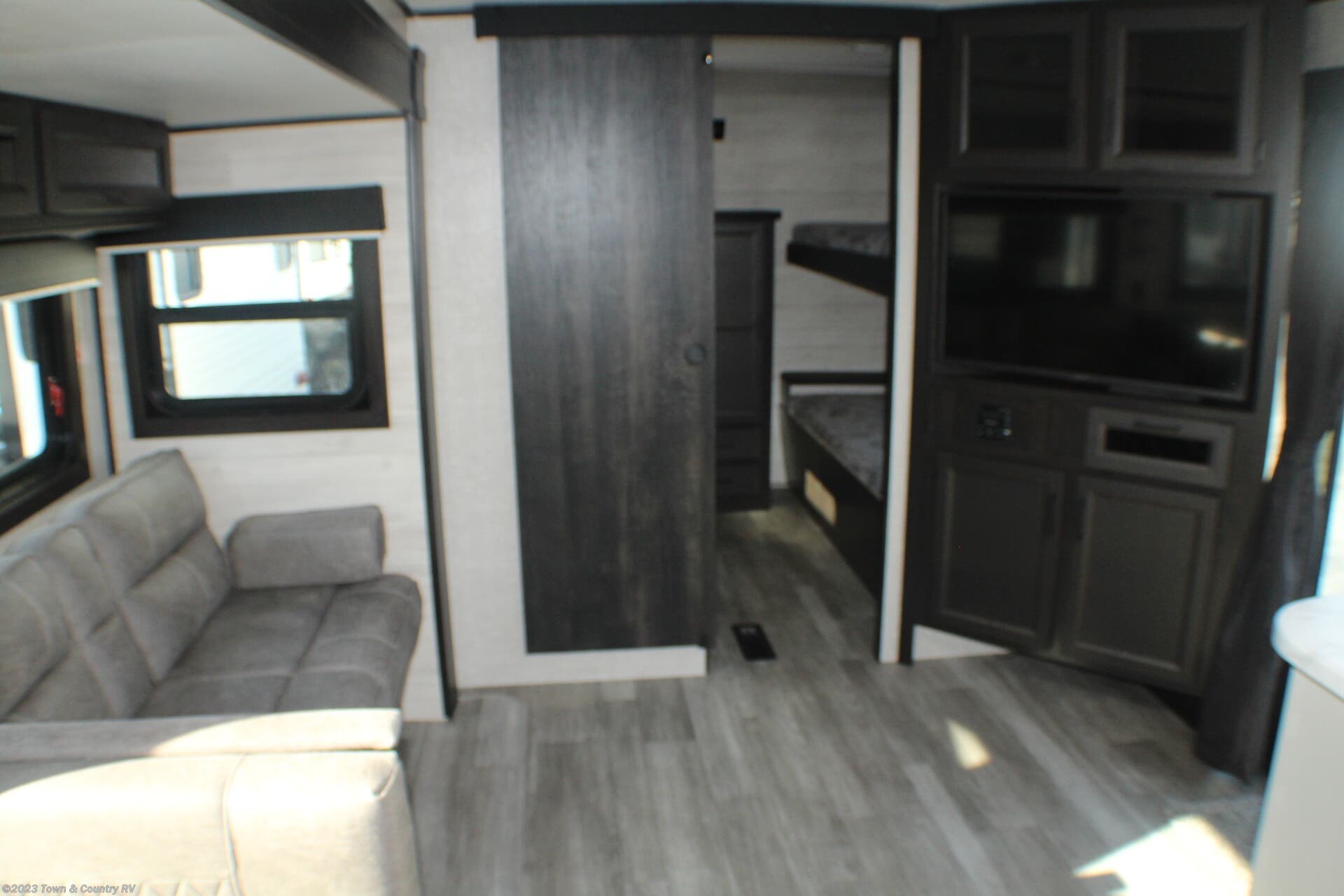 Inside this RV rental: a cozy living area with a sofa, TV, and bunk beds visible through a sliding door.. Jayco Jay Flight 2022