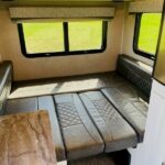 This RV rental interior features a comfortable dinette area with seating that converts to a bed, ideal for travel and camping.. Forest River Rockwood Geo Pro 2018