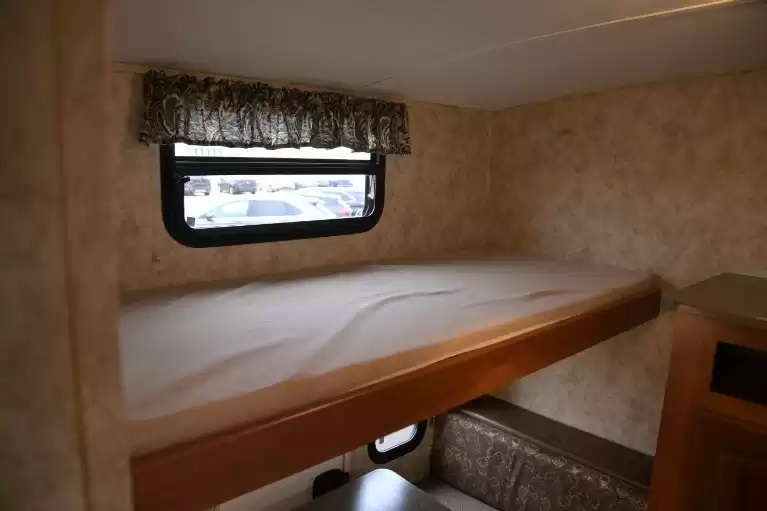Cozy bunk bed area in an RV rental, complete with a window, lower seating, and convenient storage for travelers.. Keystone RV Cougar 2011