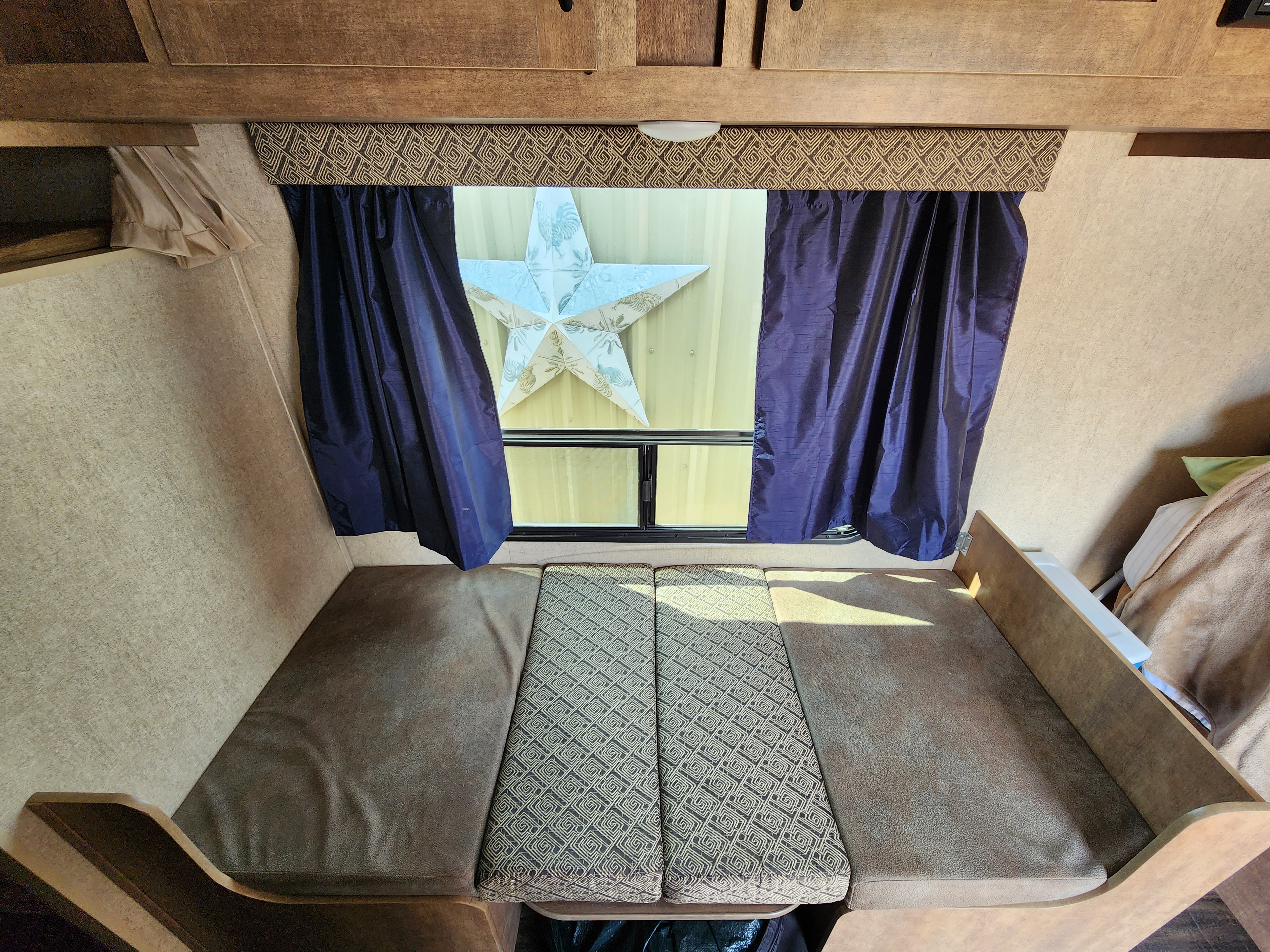Cozy RV rental sleeping area with plush cushions, window curtains, and a decorative star, ready for your travels.. Starcraft Launch Mini 2017