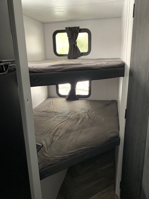Inside an **rv rental**, two stacked bunk beds with windows and tie-back curtains offer a compact sleeping area.. Forest River Salem FSX PLATINUM 2021