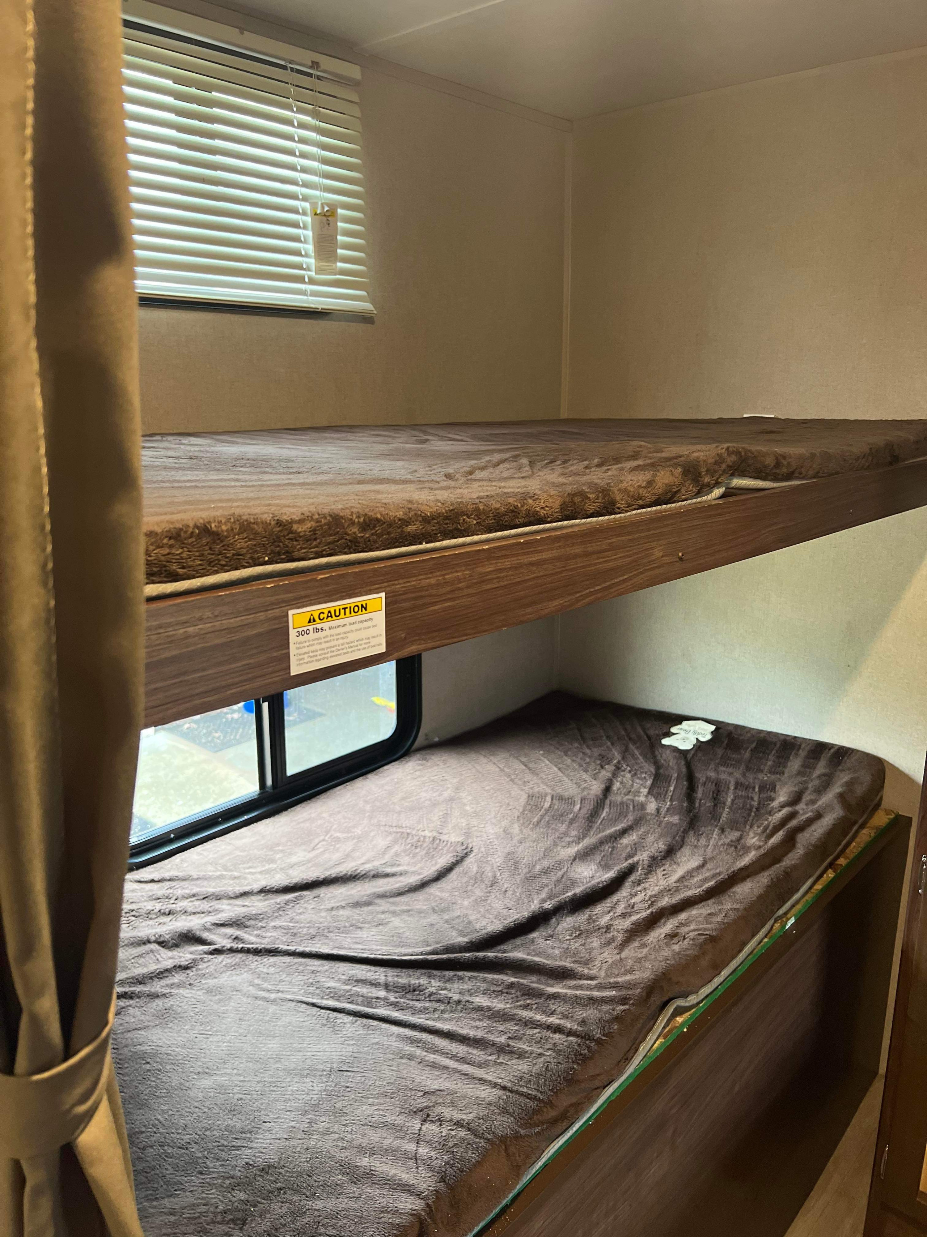 Cozy bunk beds within an RV rental, showing a 300 lbs. max load sign and window. Ideal for camper sleeping.. Dutchmen Coleman 2018