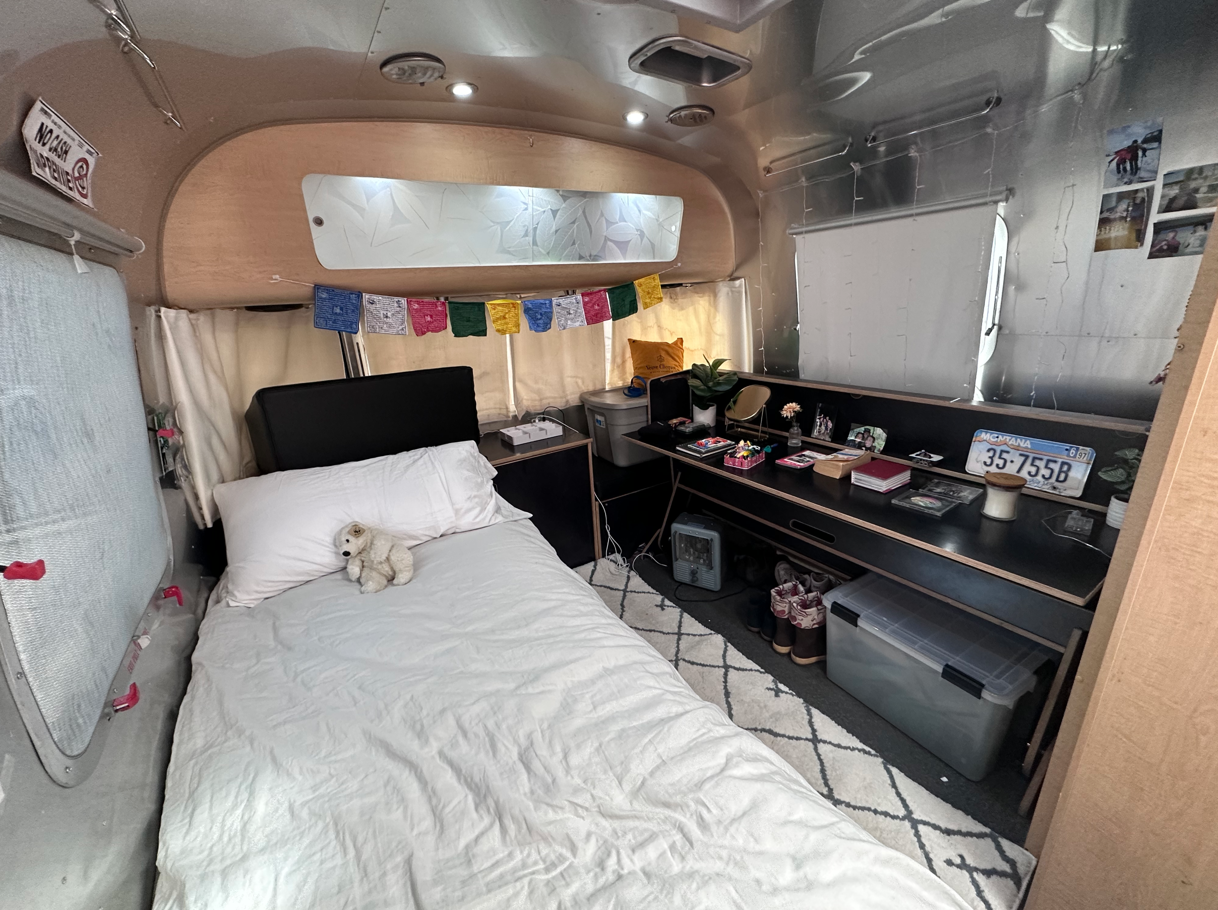 Cozy RV rental interior featuring a bed, desk area with personal items, and compact living space for travelers.. Airstream Eddie Bauer 2014