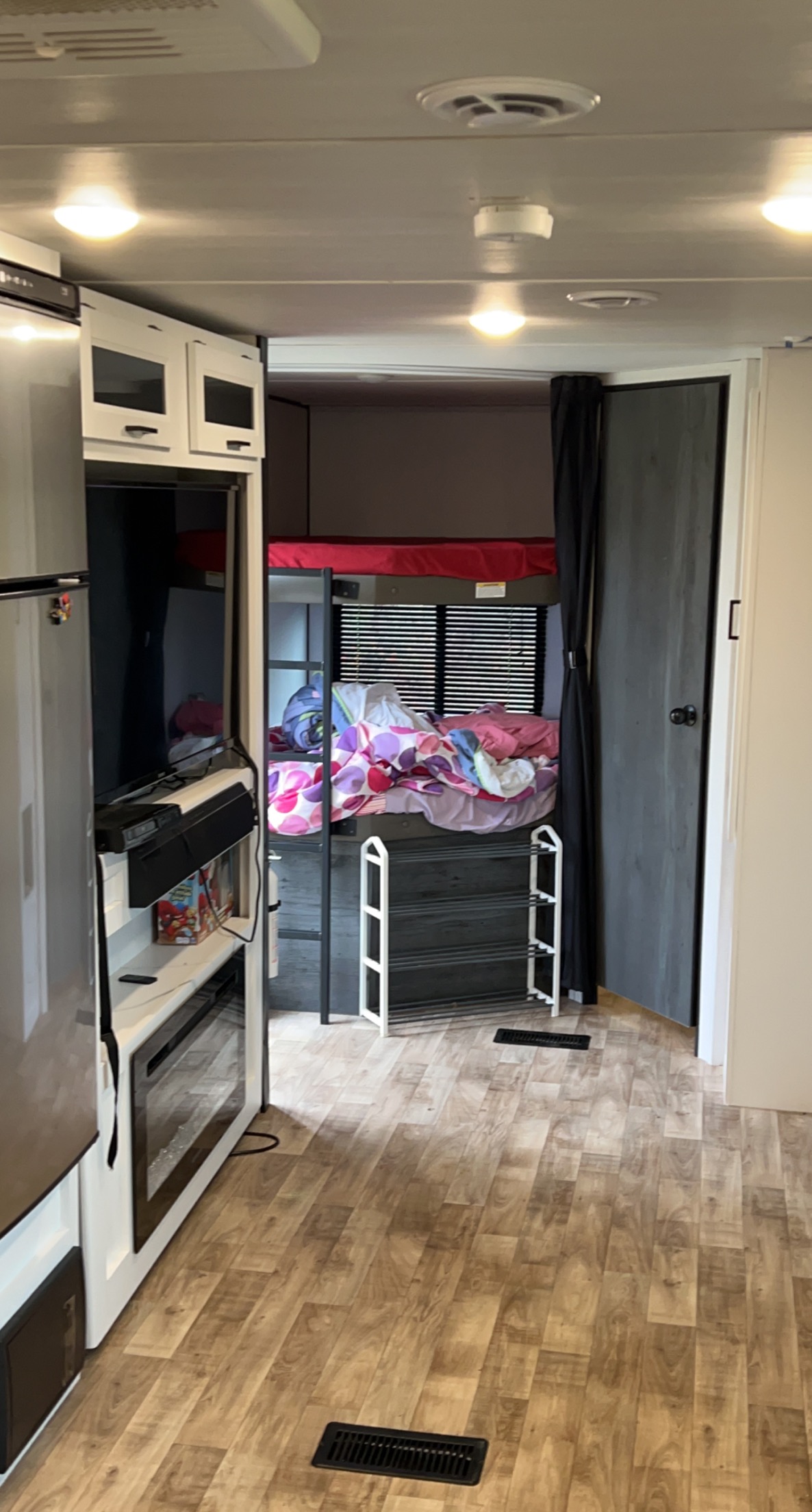 RV rental interior features a compact kitchen, TV area, and bunk beds with colorful bedding. Wood-look flooring throughout.. Keystone RV Hideout 2022