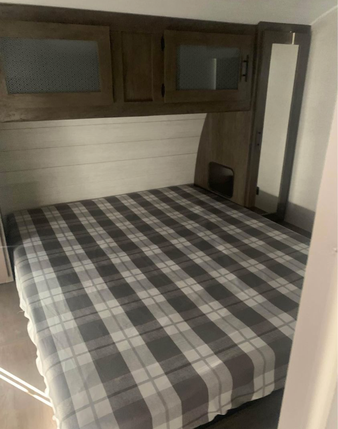Cozy RV rental bedroom with a plaid bed, overhead cabinets, and compact storage, perfect for travel accommodations.. Forest River Salem 2021