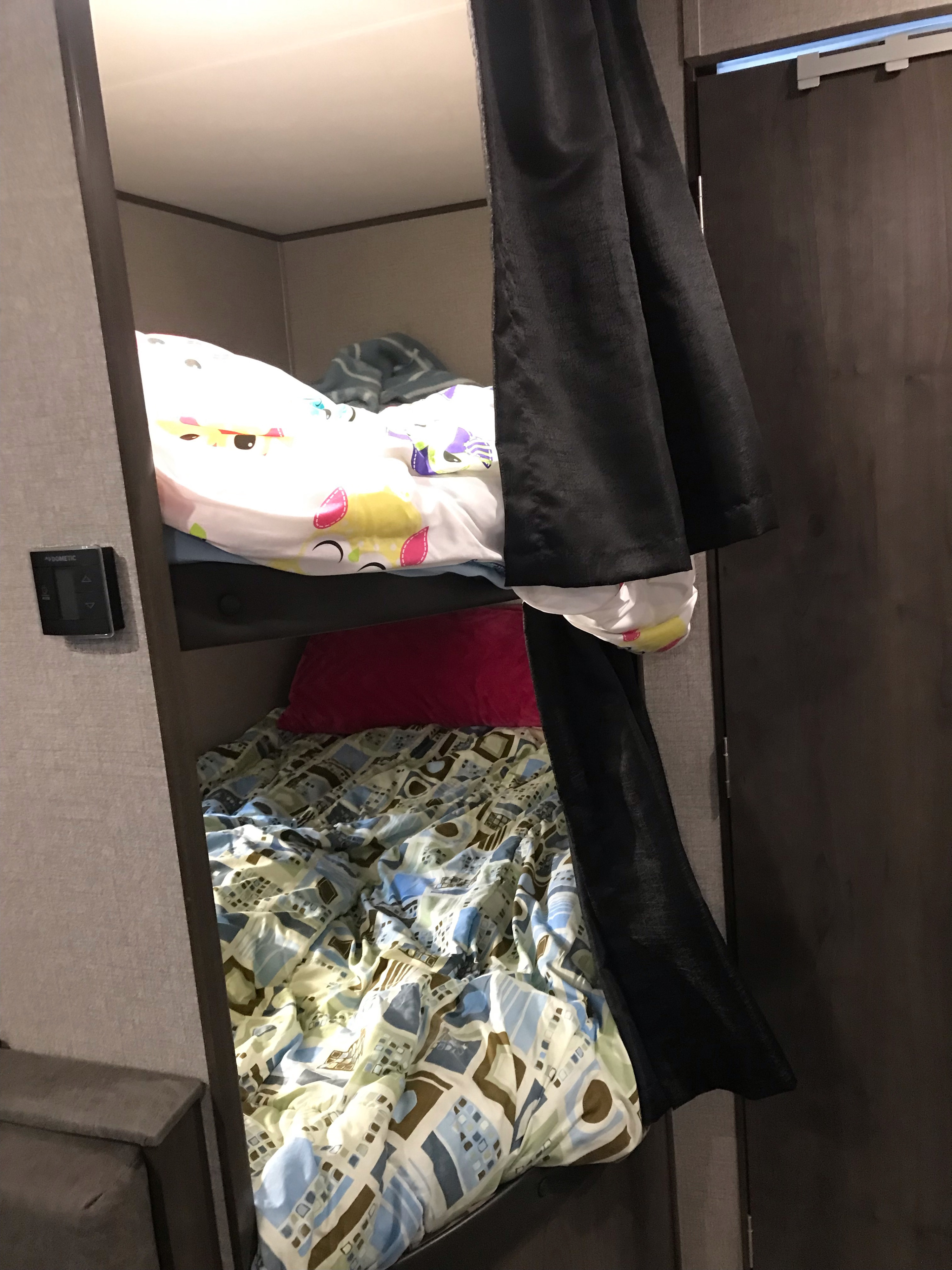 RV rental bunk beds with colorful bedding and a privacy curtain, offering compact sleeping space.. Jayco Jay Flight SLX 2020