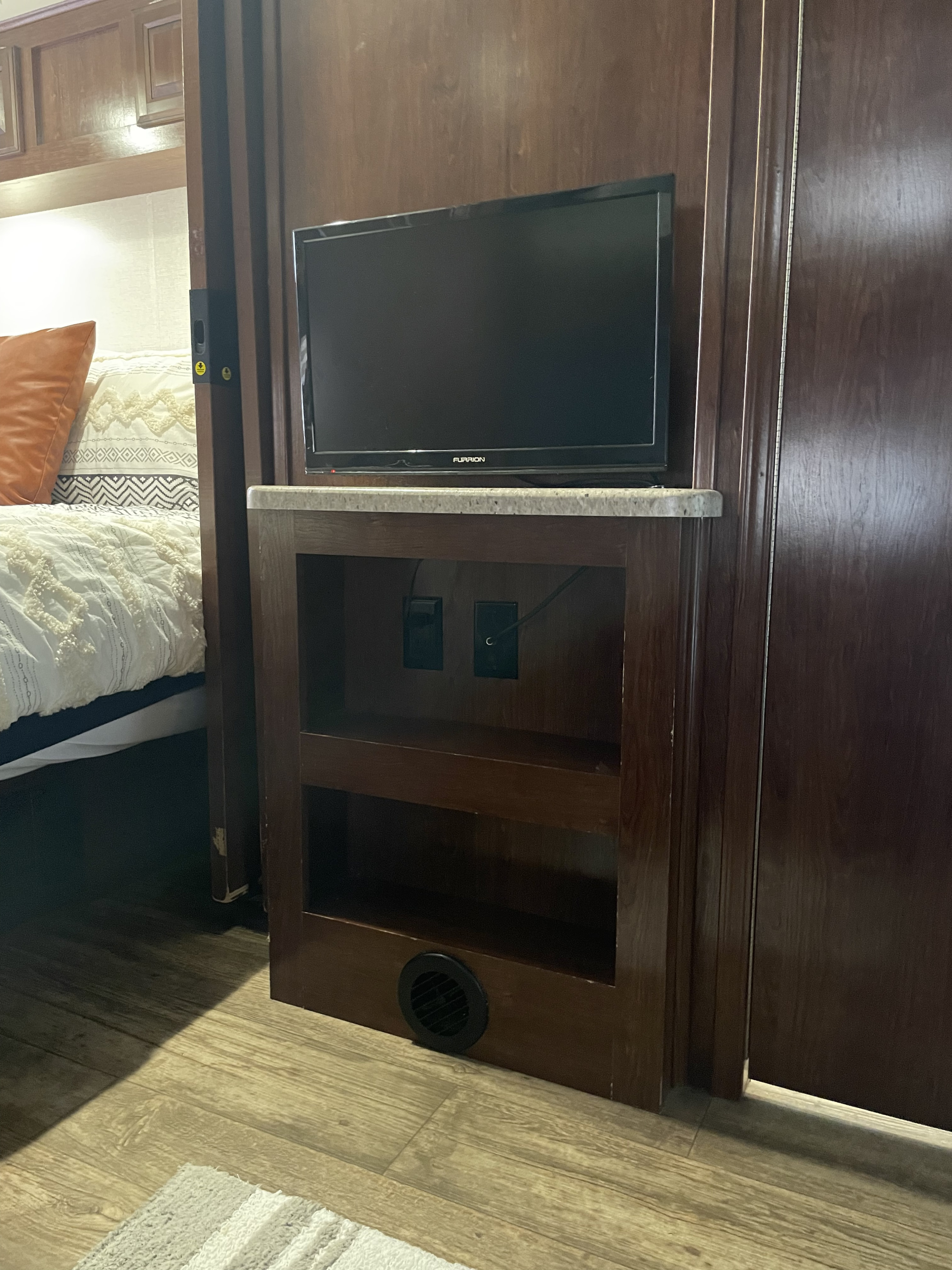 Inside an RV rental: view of a compact entertainment center with a TV, storage, and adjacent bedroom access.. FR3 FR3 Motorhome 2018