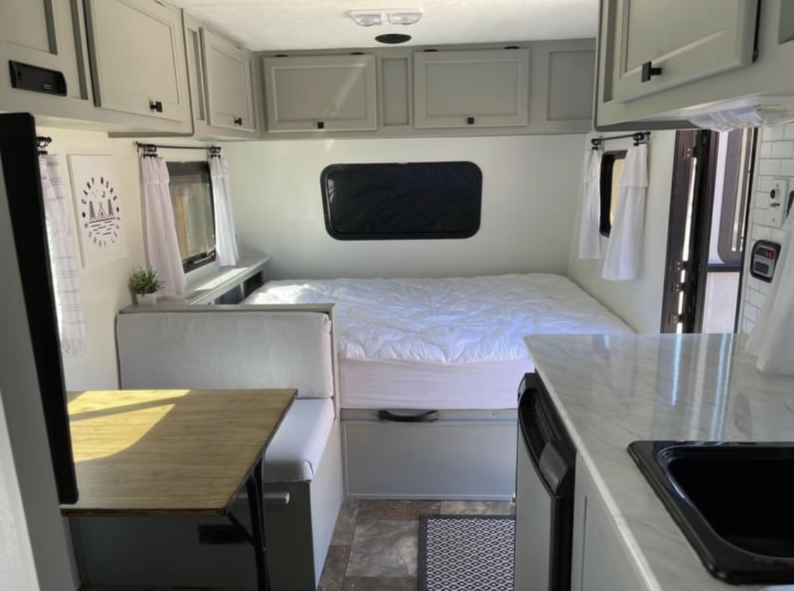 Bright, modern RV rental interior featuring a comfortable bed, dinette seating, and compact kitchen.. Forest River Viking 2015