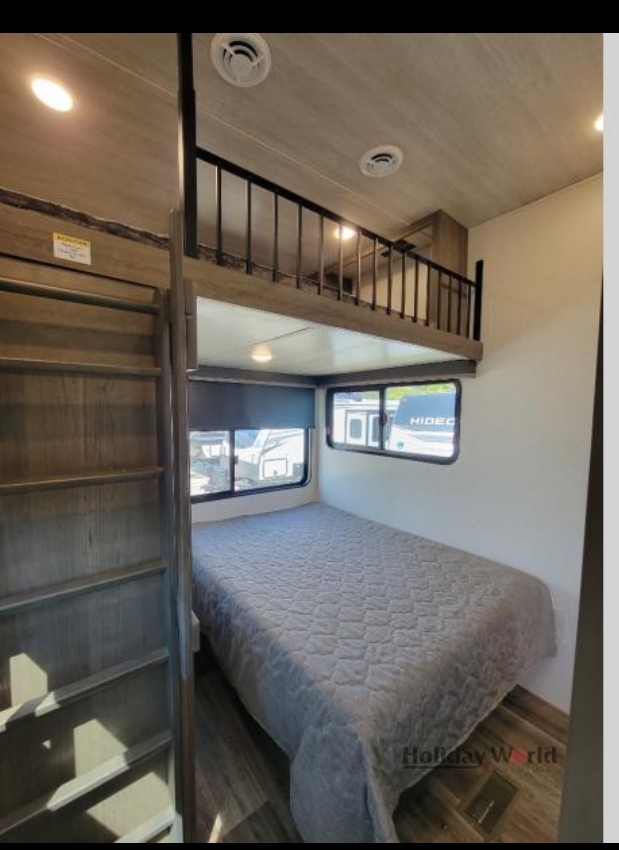 Experience the comfort of this RV rental, featuring a lower bed, ladder access to a loft, and large windows.. Keystone Cougar 2023