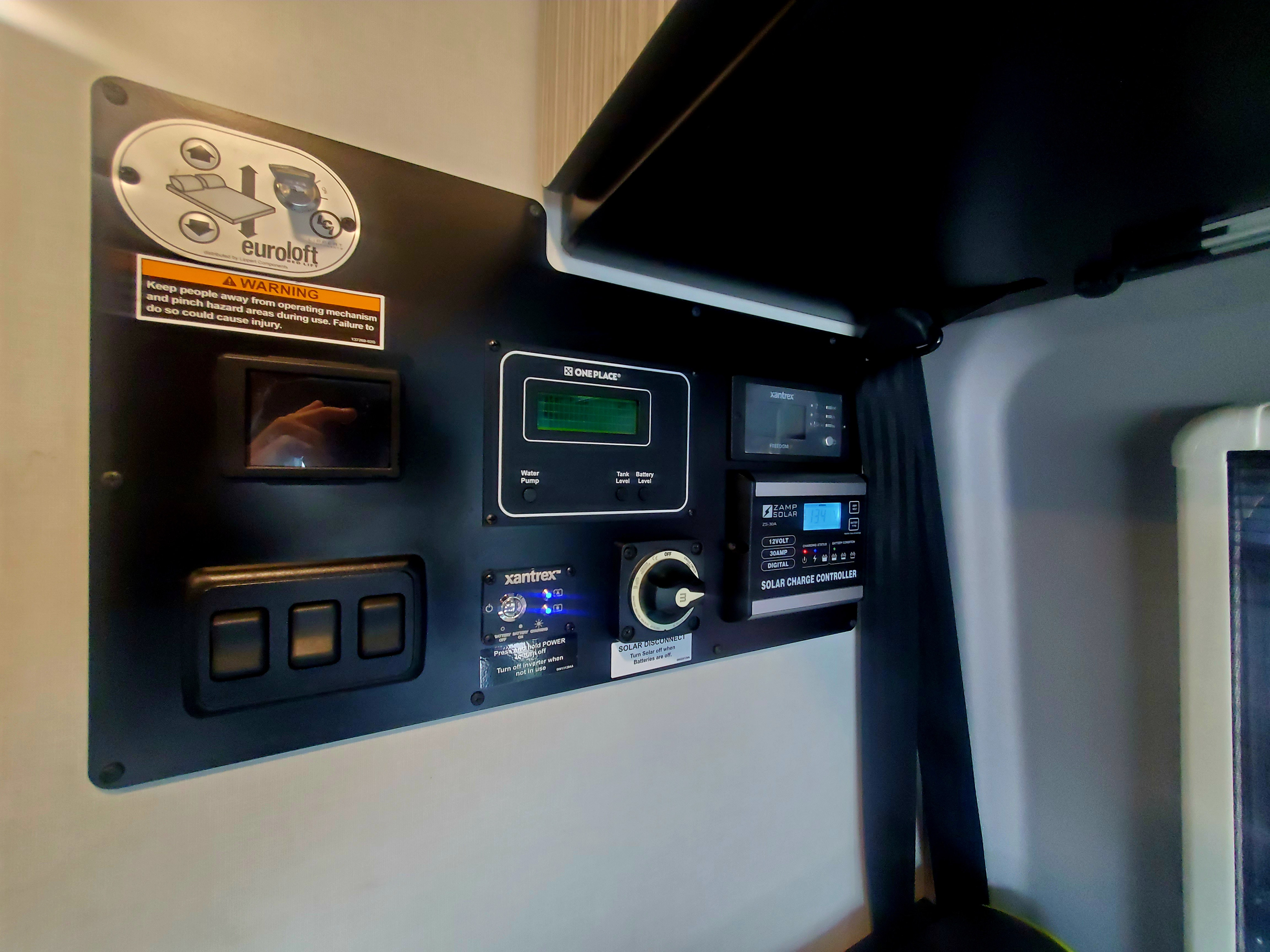 RV rental control panel: Euroloft bed lift, Zamp Solar charger (13.4V), Xantrex inverter, water/tank/battery levels.. Winnebago Revel 2020