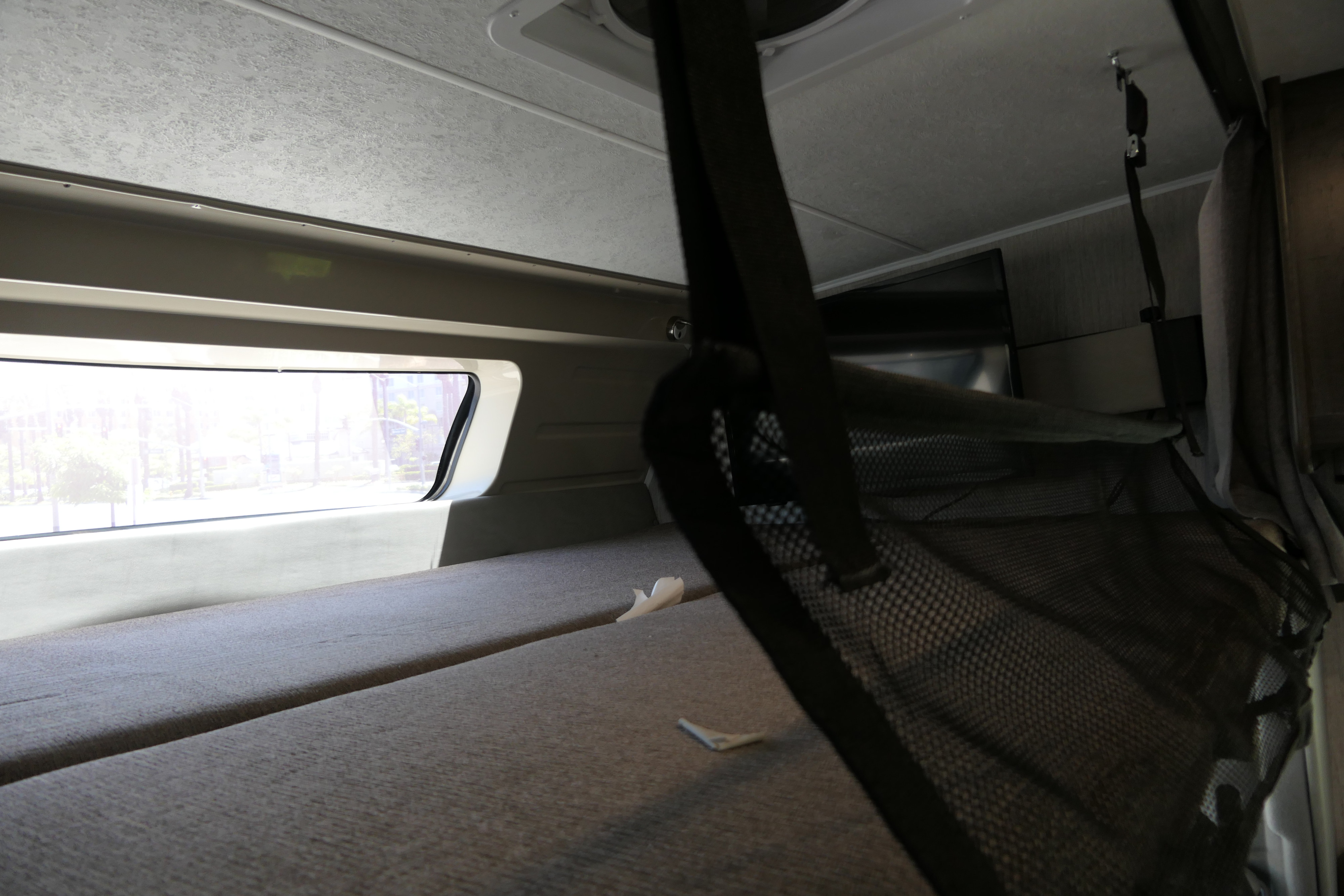 RV rental: Interior bunk bed with a window, soft cushions, and a hanging safety net. Bright outdoor view.. Coachmen Leprechaun 2021