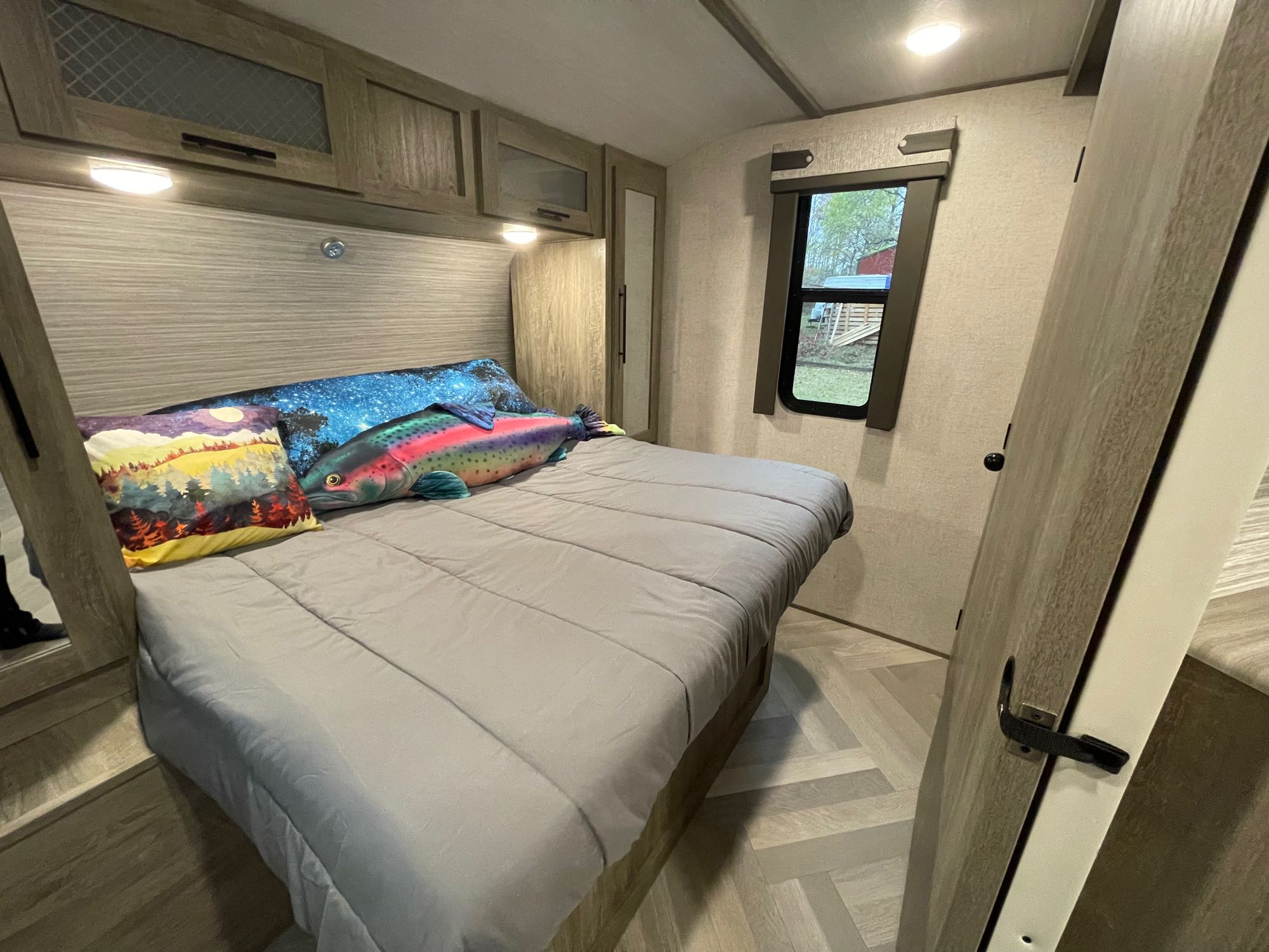 Inviting RV rental bedroom: cozy bed, overhead storage, window view, and unique fish pillow.. Forest River Salem Hemisphere HL 2021