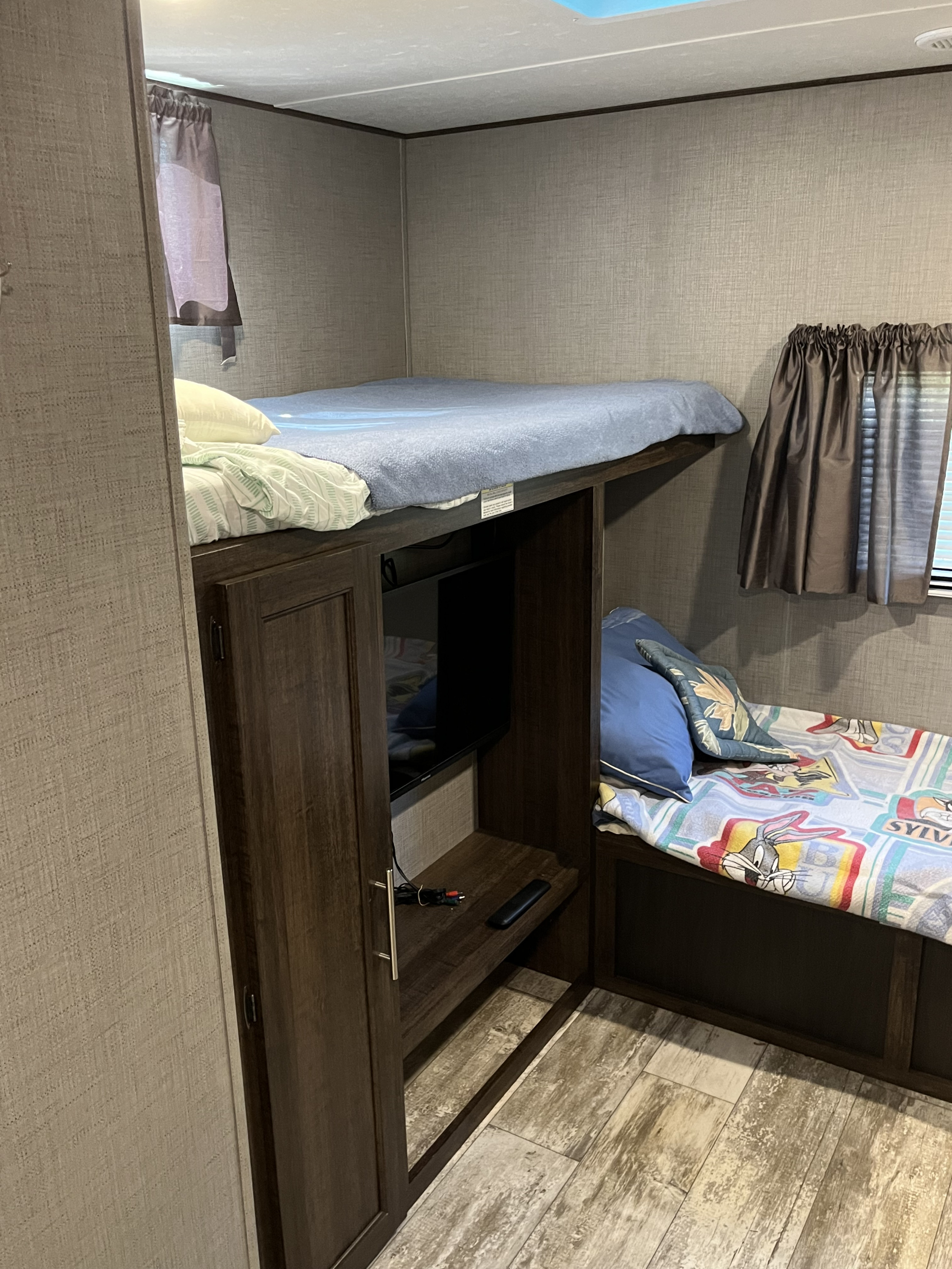 Cozy bunk beds and TV setup in an RV rental, perfect for family adventures.. Crossroads RV Zinger 2019