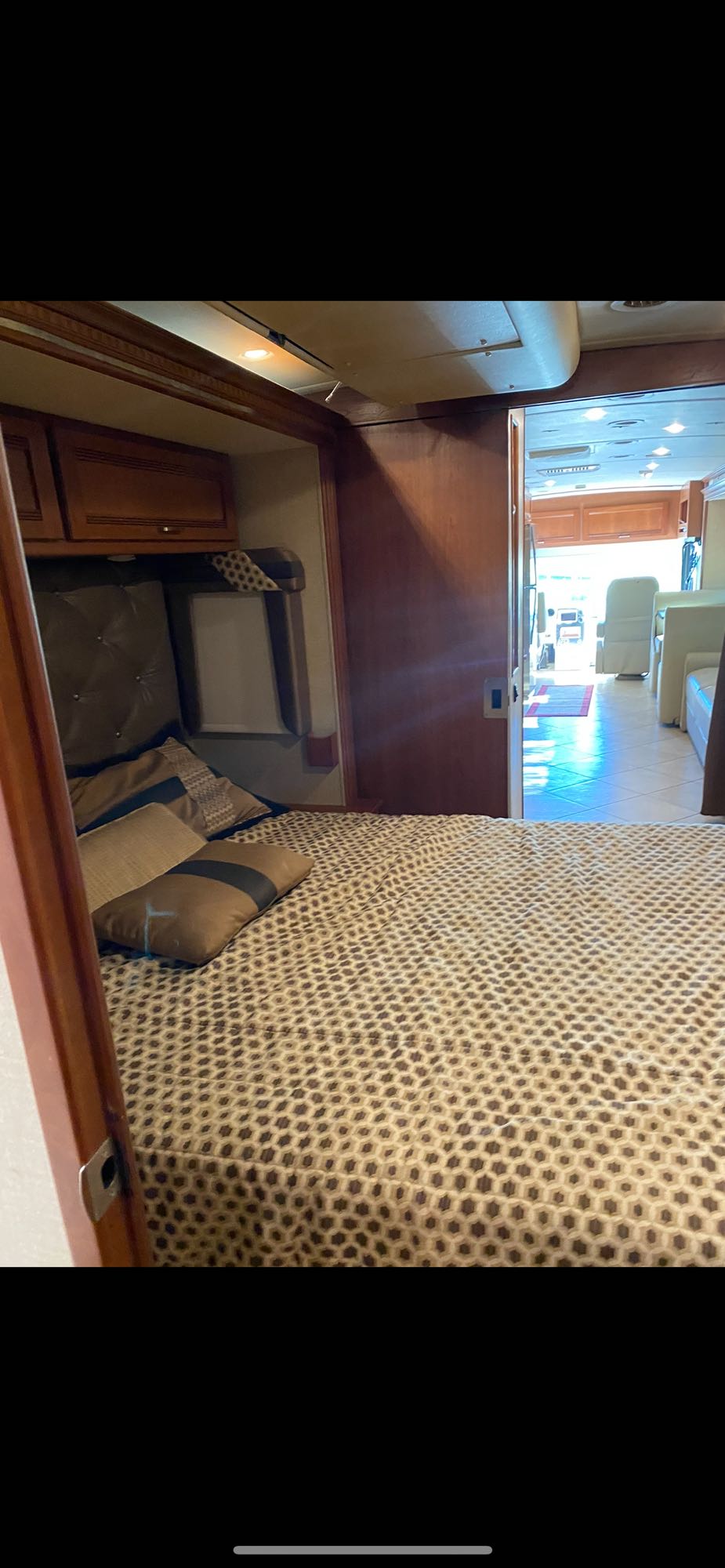 Spacious RV rental bedroom features a patterned bed, and a partially open door revealing the bright living area.. Winnebago Forza 2014