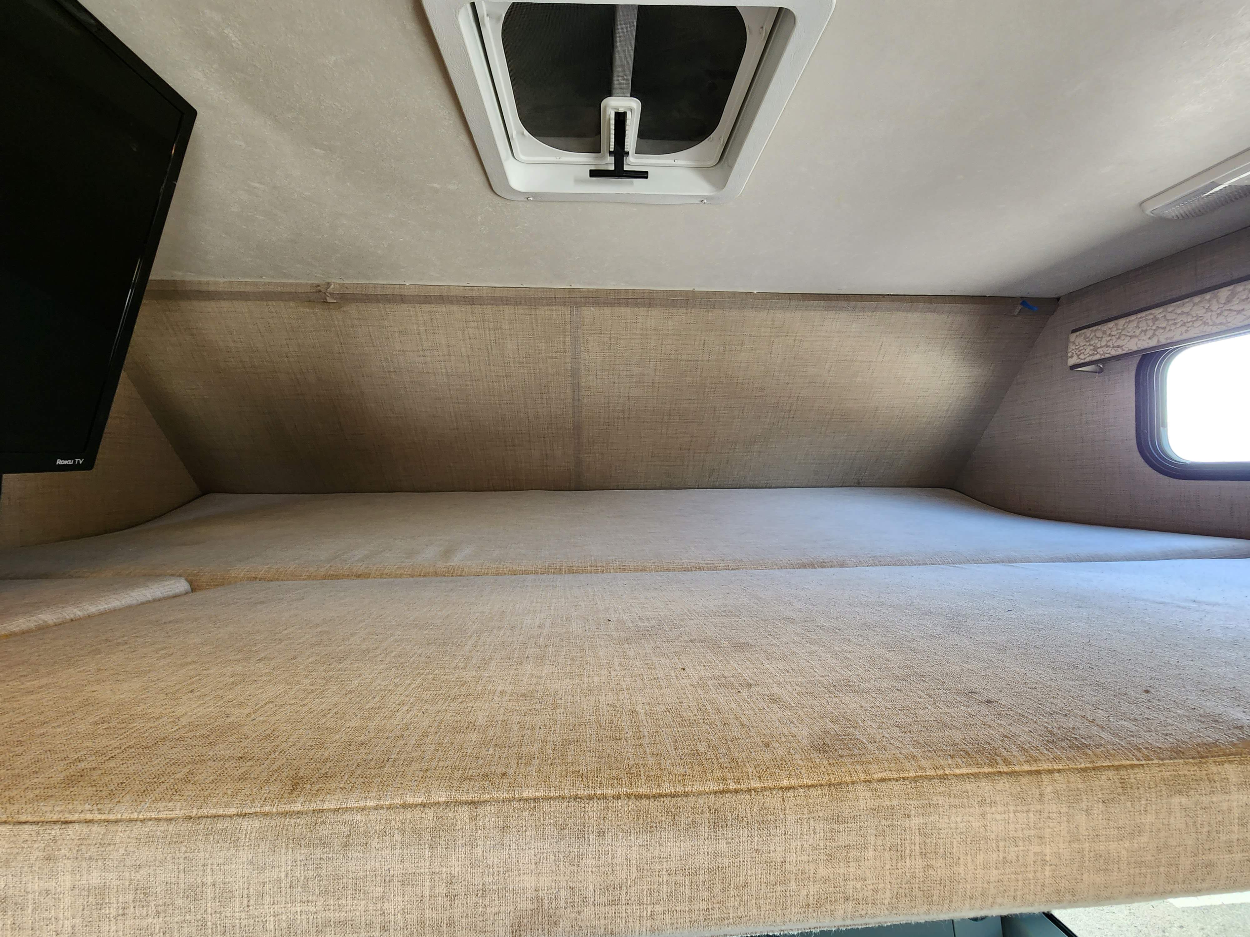 Spacious cab-over bunk in this RV rental, complete with a cozy bed, TV, ceiling vent, and side window.. Wayfarer Wayfarer Motorhome 2020