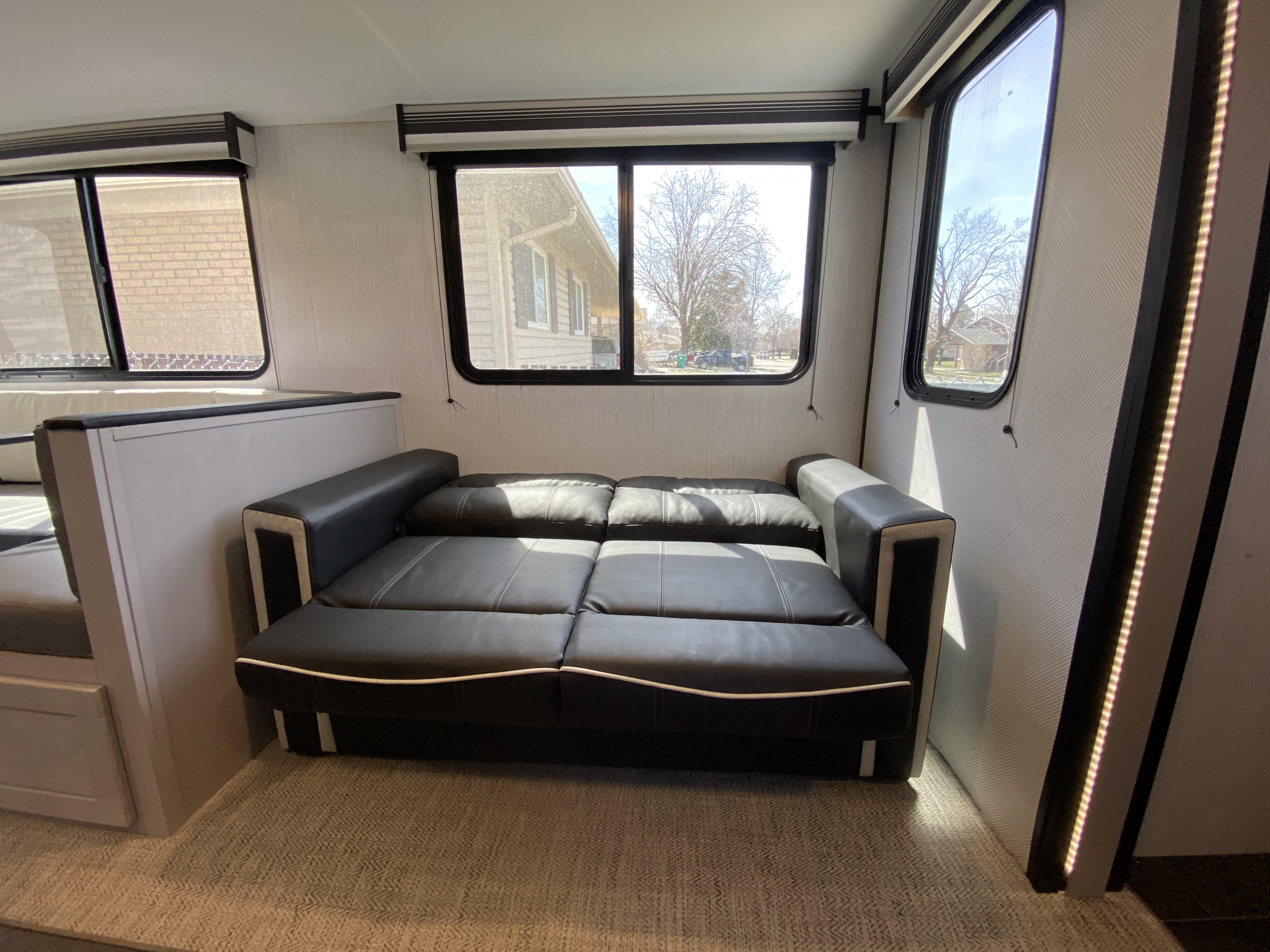 RV rental interior featuring a black leather sofa bed, dinette, and bright windows for a comfortable living space.. Heartland RVs Mallard 2022