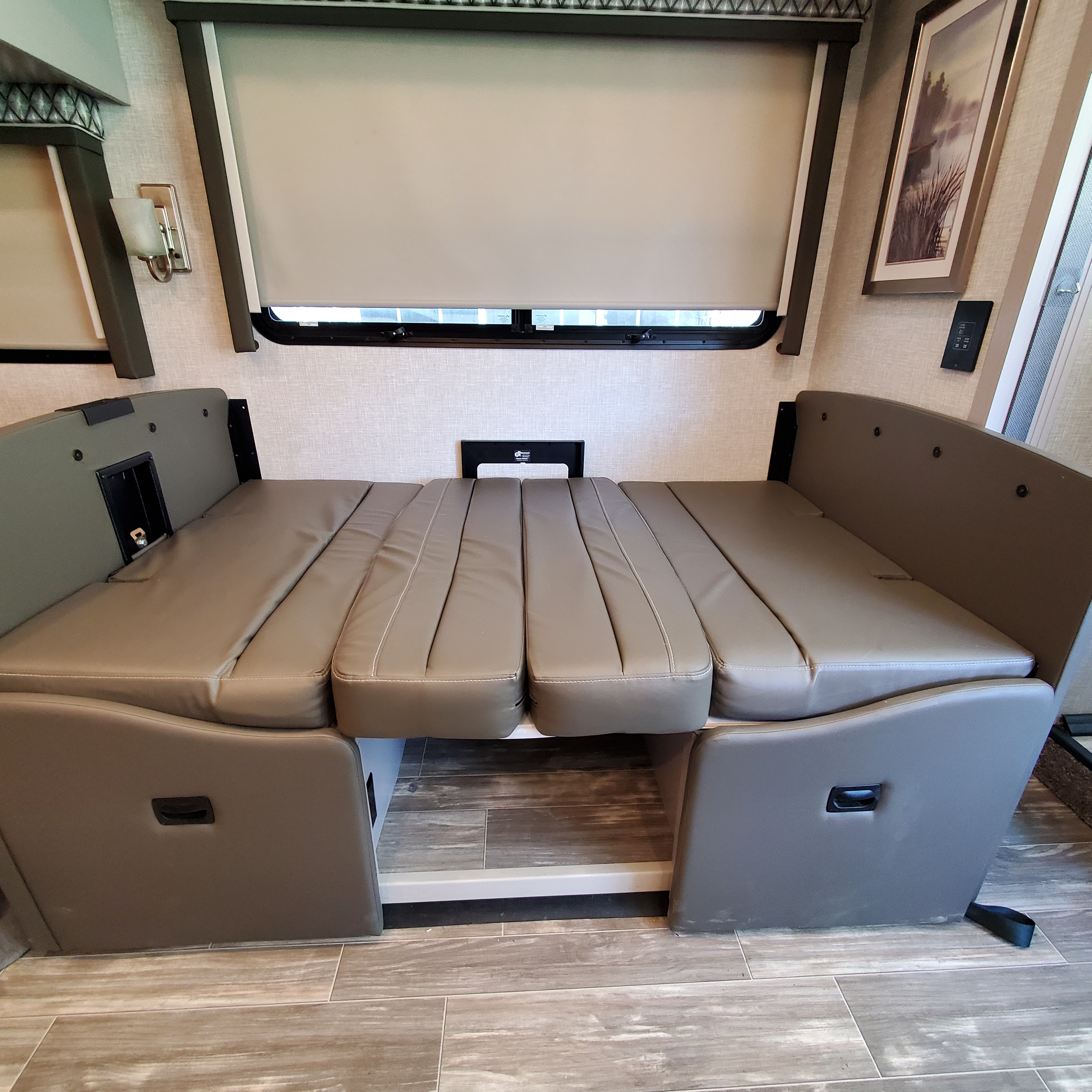 This RV rental features a versatile dinette transformed into a comfortable bed with neutral upholstered cushions and wood flooring.. Thor Hurricane 2022