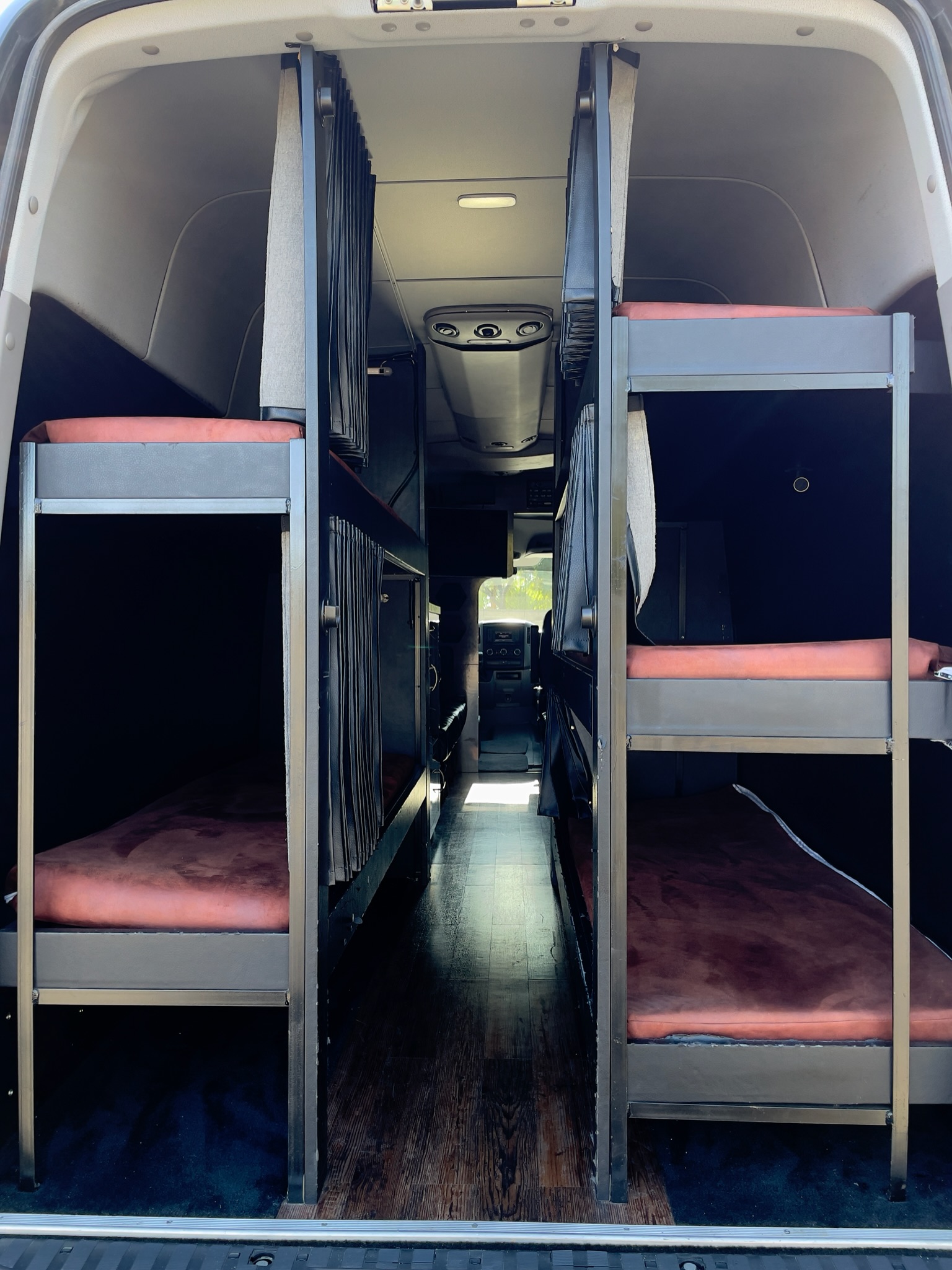 RV rental's interior: two rows of bunk beds with brown mattresses create a narrow central aisle inside this van.. Mercedes-Benz Sprinter 2014