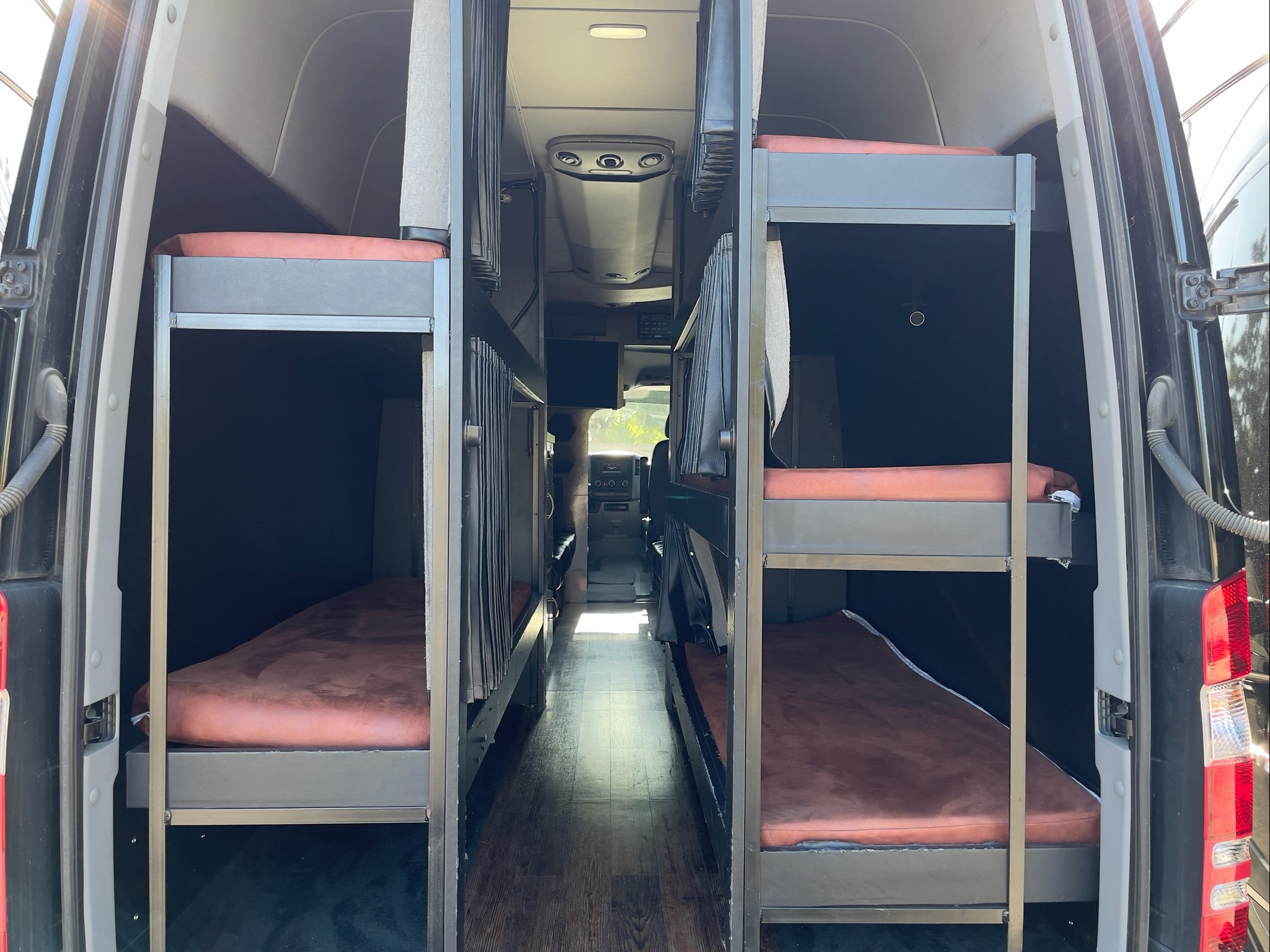 Spacious RV rental interior featuring two sets of bunk beds along a central aisle, ideal for group travel.. Mercedes-Benz Sprinter 2014