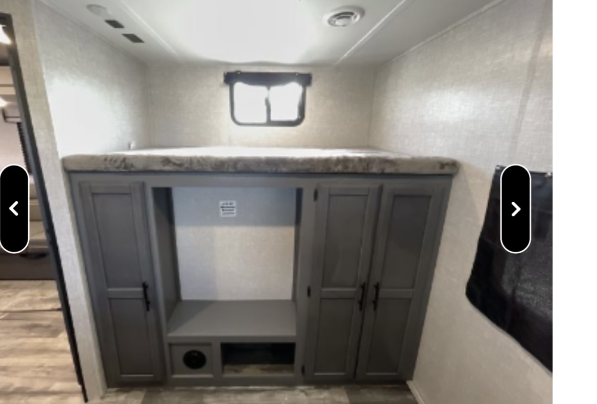 RV rental interior features a bunk bed above gray cabinets, offering storage and an entertainment space.. Crossroads RV Volante 2021