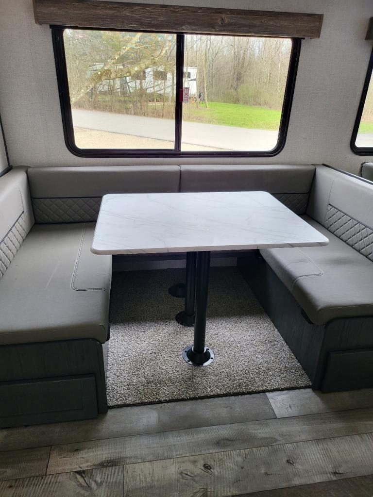 RV rental: Modern U-shaped dinette with grey cushions, white table, and scenic park views through large windows.. Aspen Trail Dutchman 2022