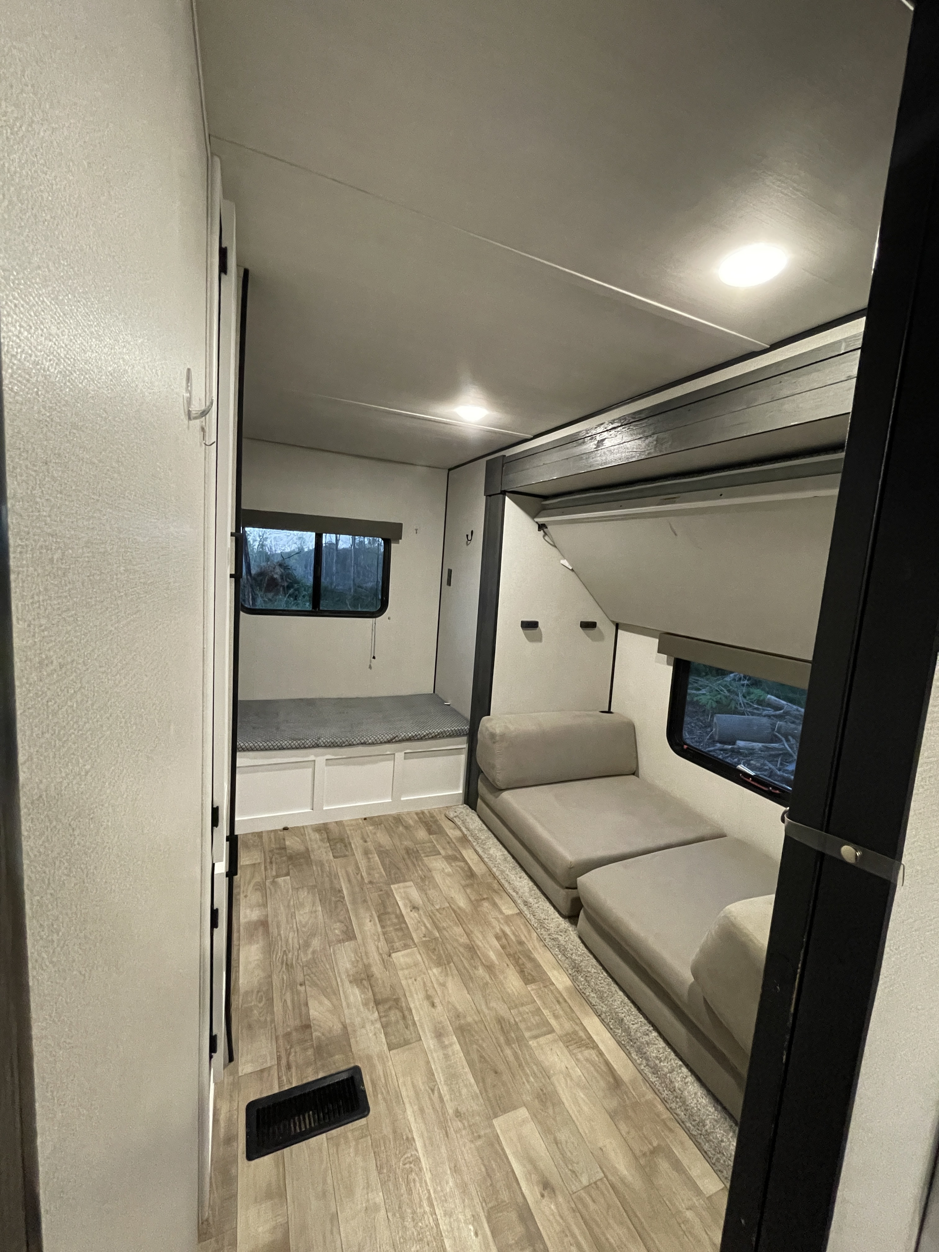 Inside an RV rental: Compact living area with a bench/bunk bed, modular seating, and wood-look floor.. Keystone RV Hideout 2022