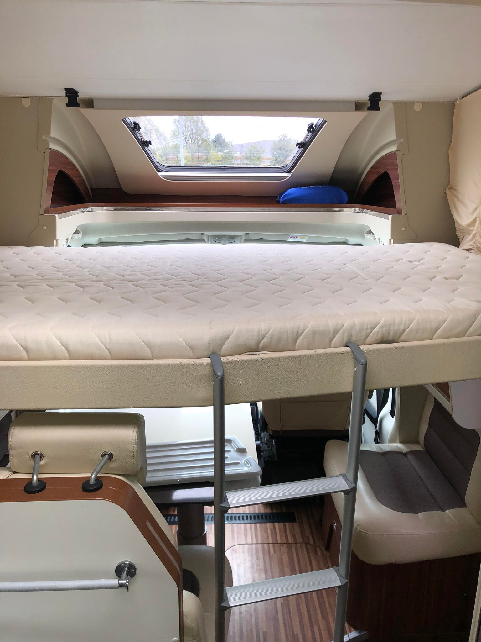 Inside an RV rental: a comfortable elevated bed with ladder and overhead skylight for scenic views.. Adria MATRIX 670 M SBC 2015
