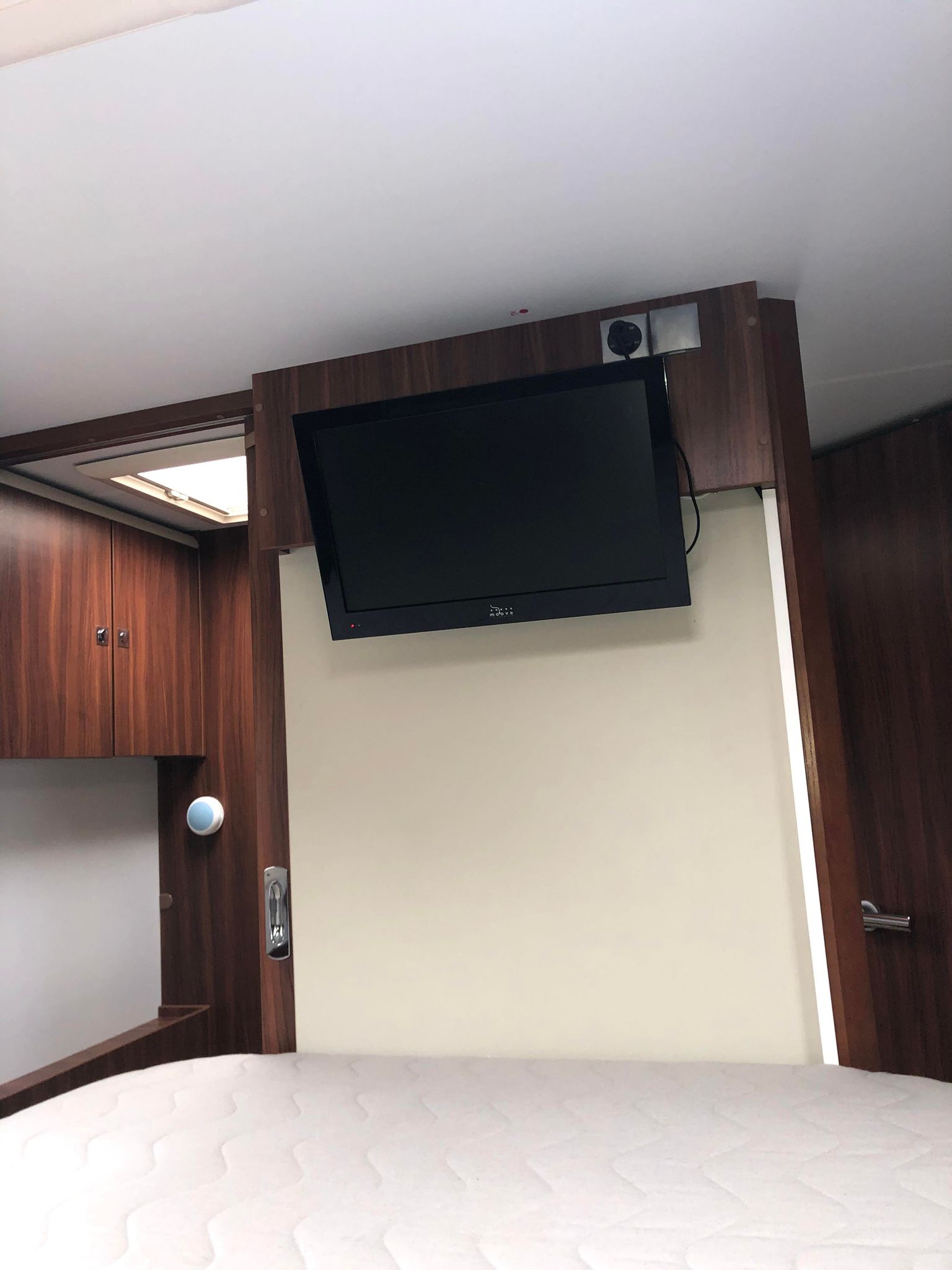 RV rental: Cozy motorhome bedroom featuring a mounted TV, dark wood cabinetry, white mattress, and skylight for comfortable travel.. Adria MATRIX 670 M SBC 2015