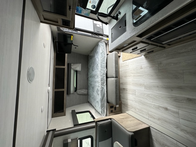 Step into this modern RV rental interior, a compact living space featuring a kitchen, dinette, and bed area with light wood floors.. Surveyor Legend 19MDBLE 2022