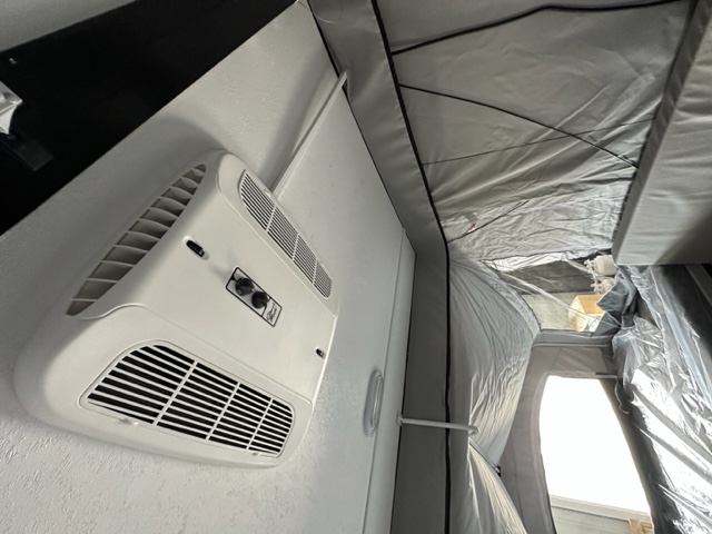 RV rental interior: Wall-mounted AC unit cools the pop-up tent sleeping area. Bright light streams from the window for comfortable camping.. Coachmen Clipper 806XLS 2022