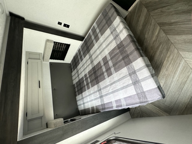 Modern RV rental bedroom: cozy plaid bed, herringbone floor, and built-in storage. Ready for your next adventure!. Salem FSX 169RSK 2022