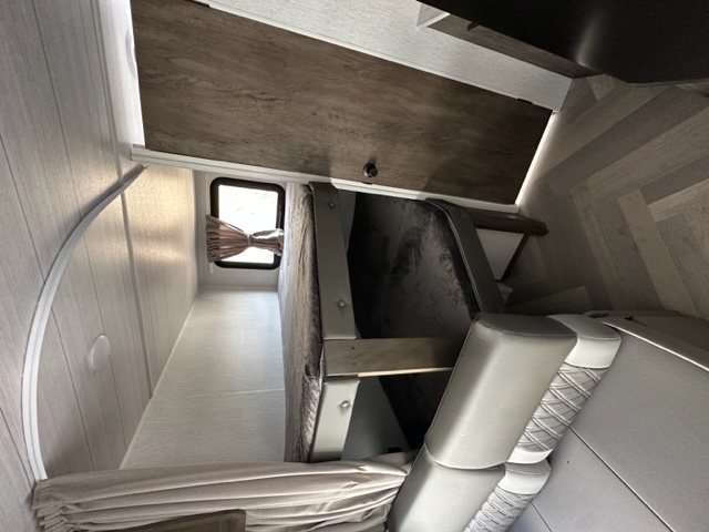 Experience comfort in this RV rental's interior, featuring a cozy bed, window with curtains, and seating area.. Salem Cruise Lite 19DBXL 2022