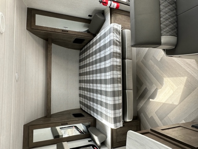 Modern RV rental interior showcasing a plaid bed, grey dinette seating, and light herringbone flooring. Comfortable and stylish.. Salem Cruise Lite 19DBXL 2022
