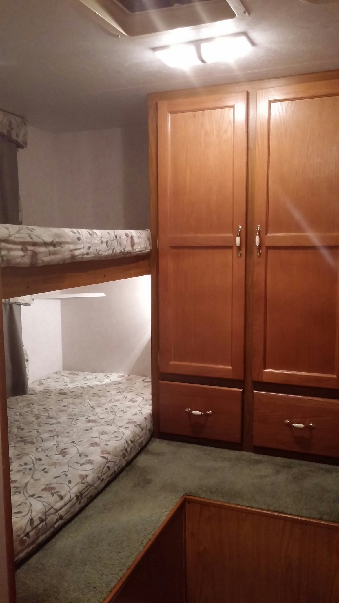 This RV rental interior offers cozy bunk beds with patterned mattresses and built-in wooden storage cabinets, perfect for family trips.. Chateau Chateau Trailer 2001