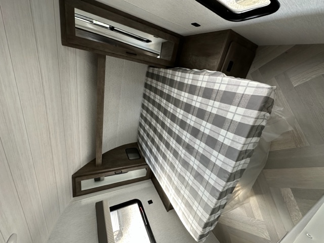 Inside an **RV rental**: a cozy bedroom with a plaid-covered bed, light wood panel walls, and built-in storage for travel.. Salem Cruise Lite 263BHXL 2022