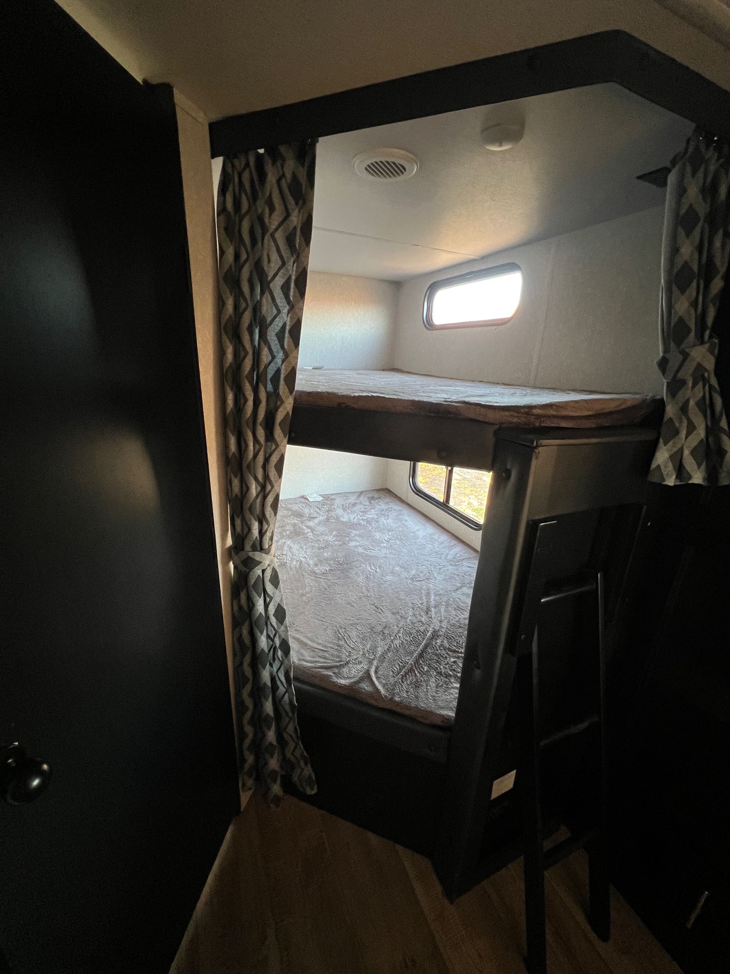 Cozy RV rental interior with double bunk beds and windows, ideal for family travel or camper adventures.. Forest River Cherokee Grey Wolf 2022