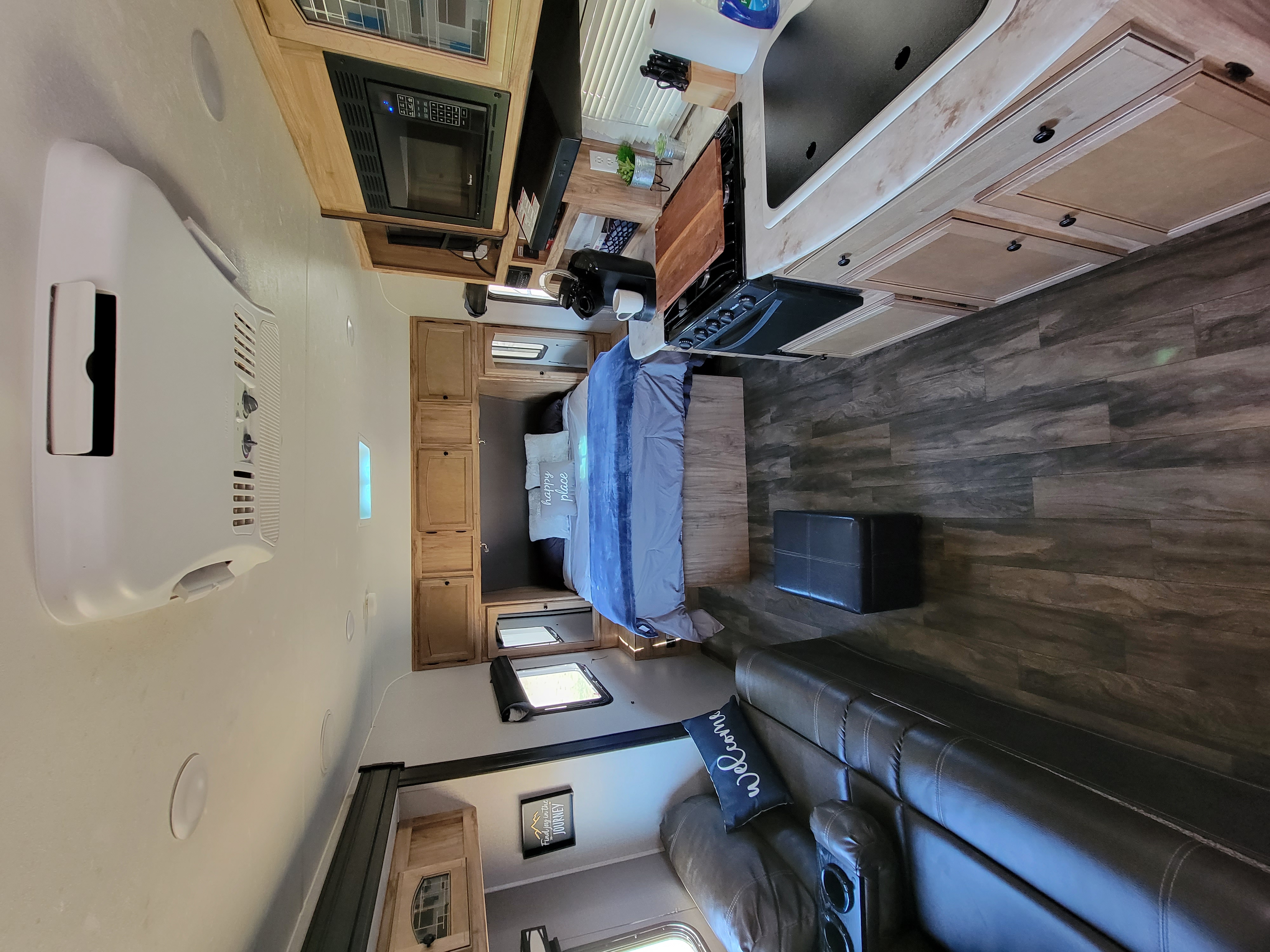 RV rental features a well-equipped kitchen, cozy bed, and living area with sofa and wood-look flooring.. Coachmen 192 RBS 2018