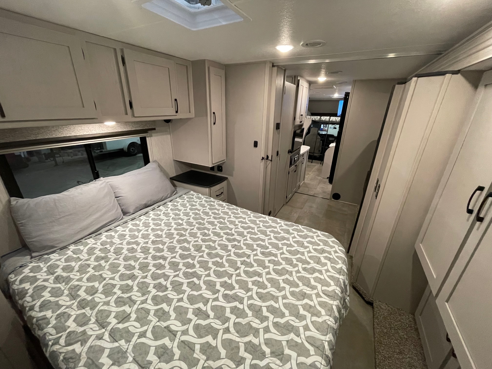 Cozy RV rental bedroom with a modern interior, featuring light cabinets and a comfortable bed for your next adventure.. Coachmen Freelander 2024